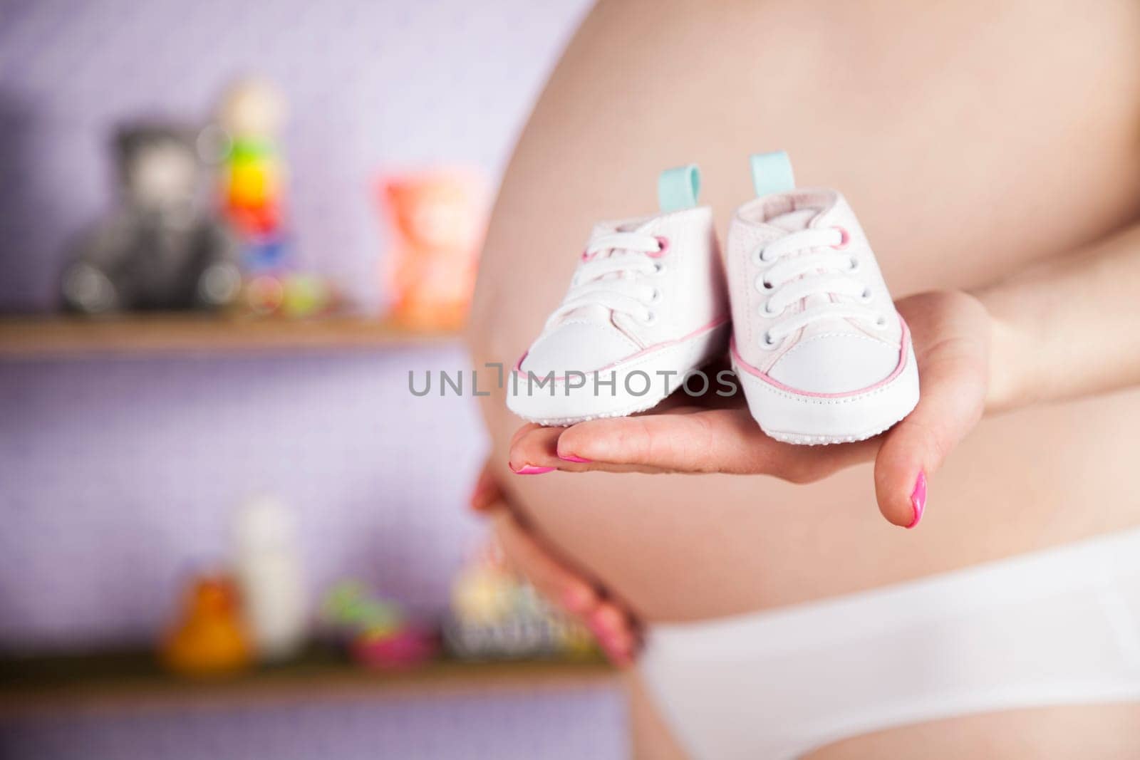 Pregnant woman holding baby shoes in her hands
