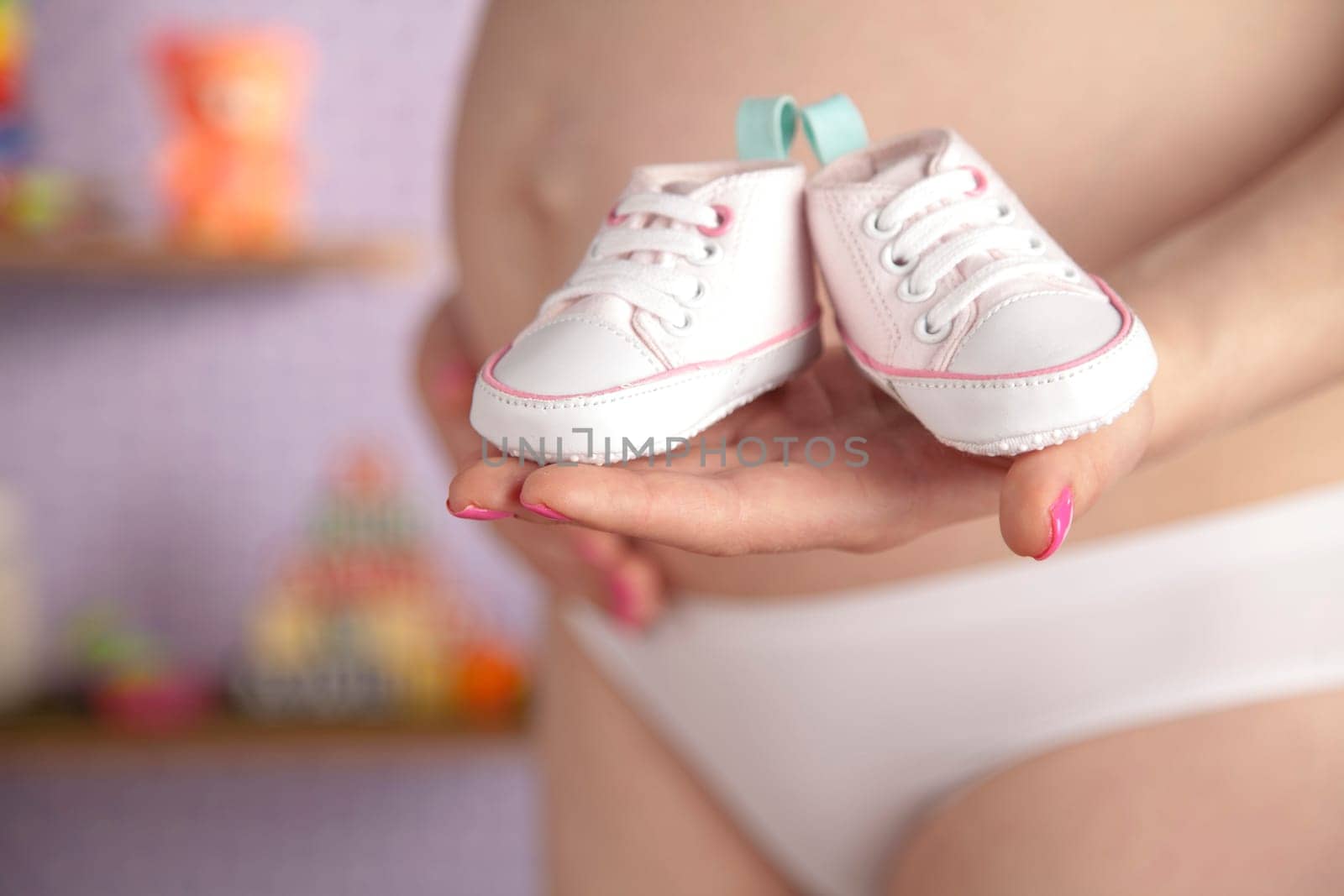 Pregnant woman holding baby shoes in her hands