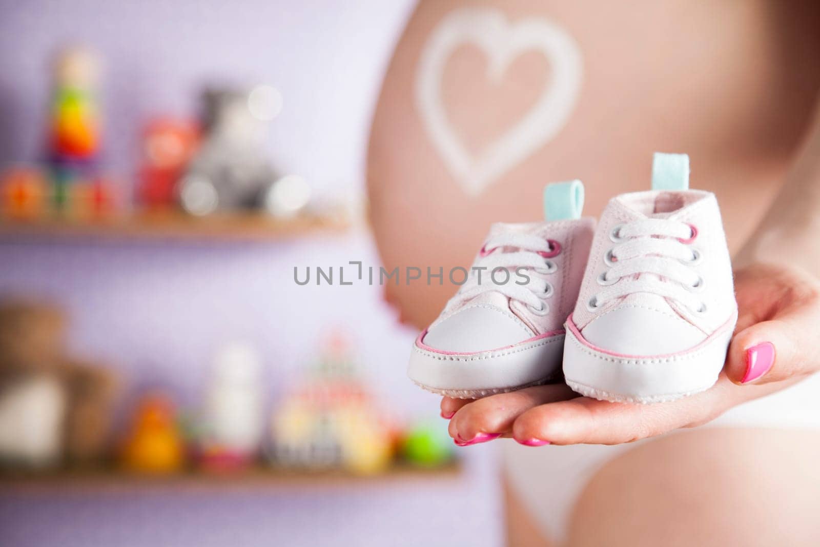 Pregnant woman holding baby shoes in her hands
