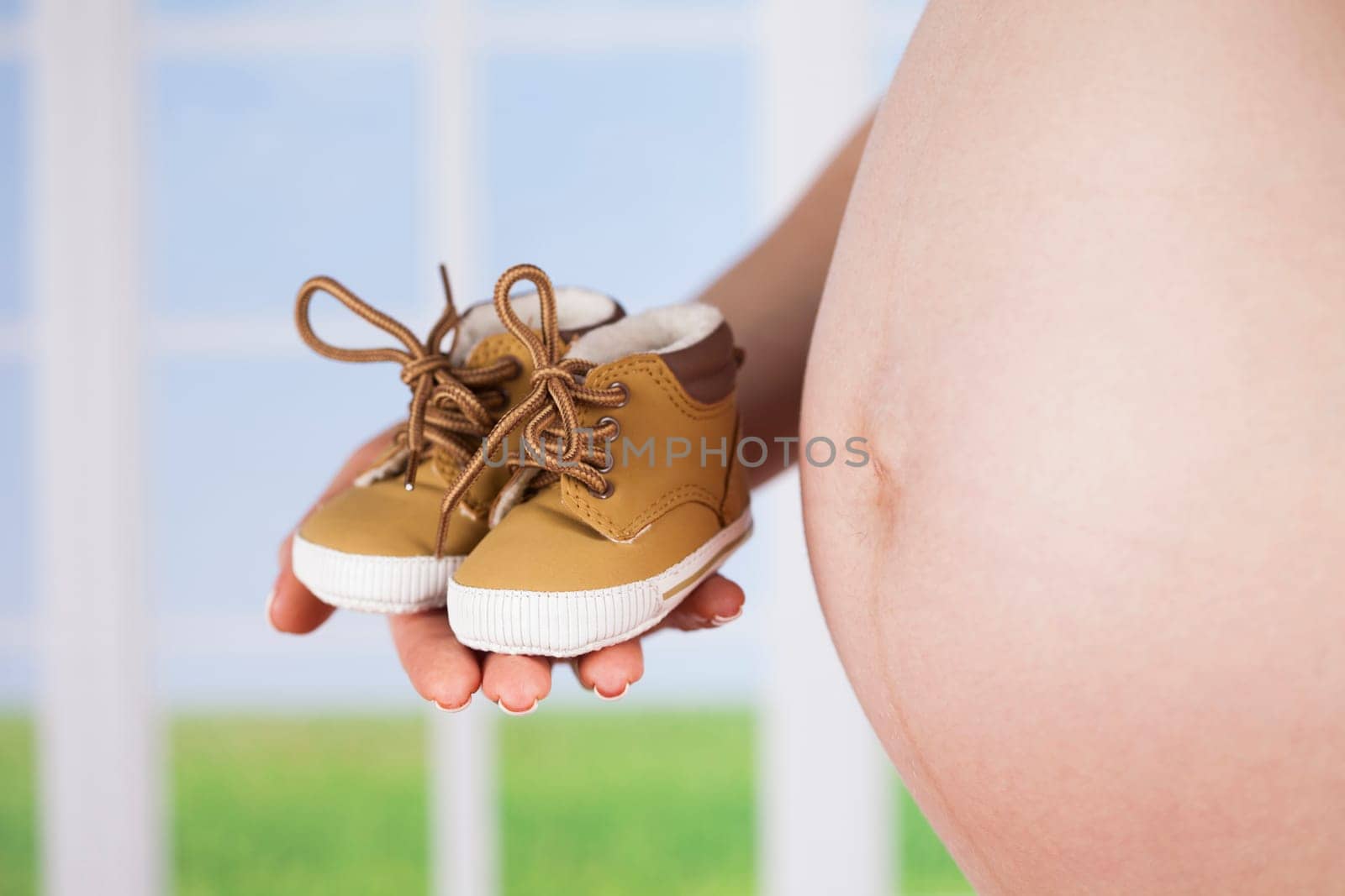 Pregnant woman holding baby shoes in her hands