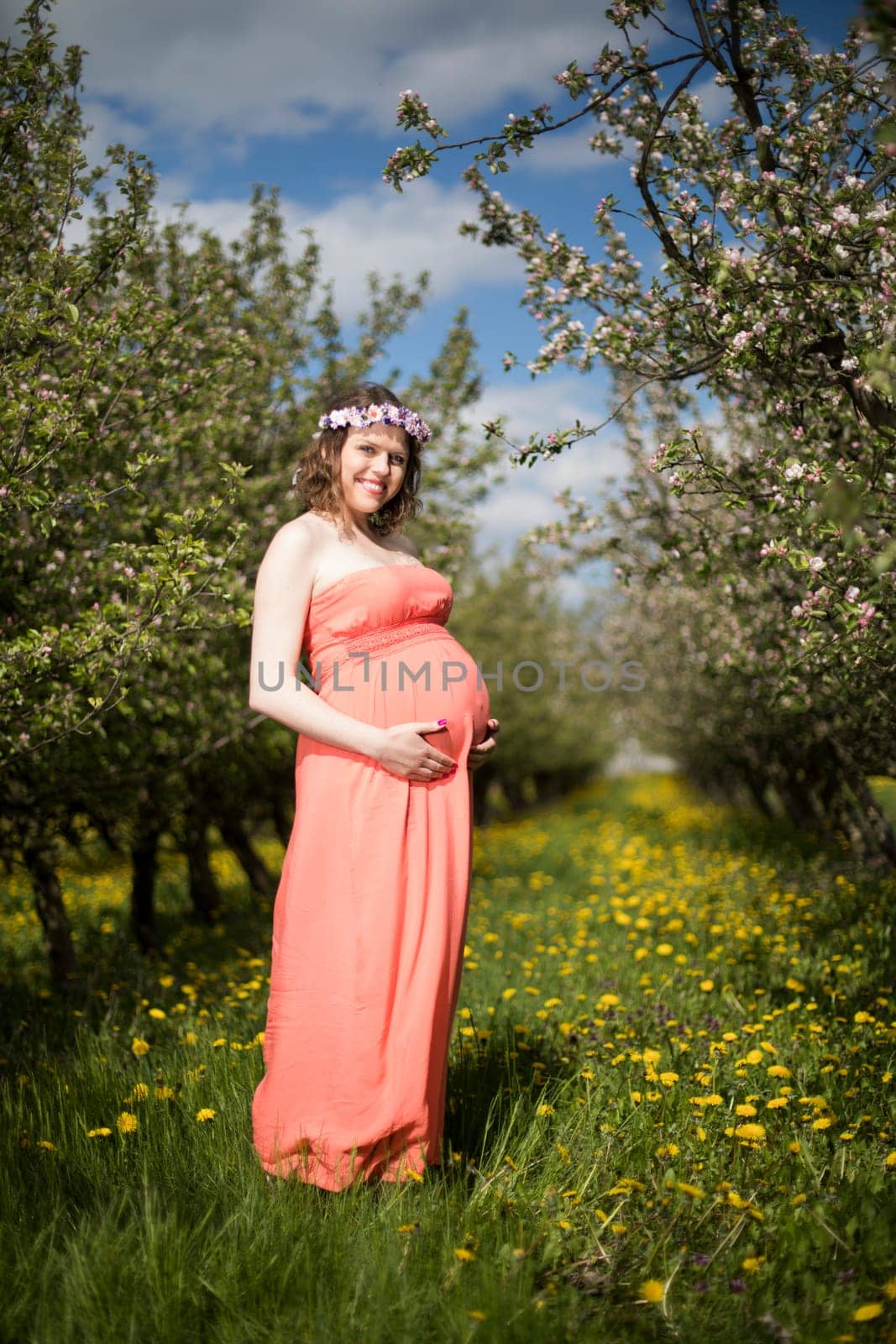 Young beautiful pregnant woman, blooming garden