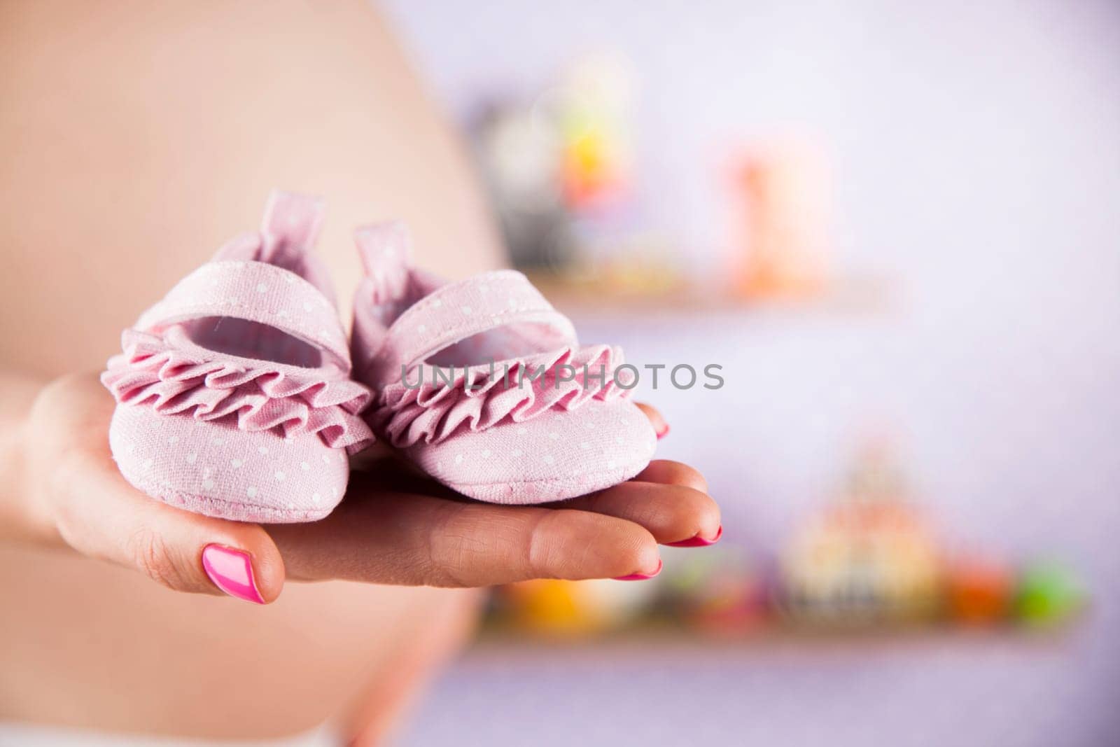 Pregnant woman holding baby shoes in her hands
