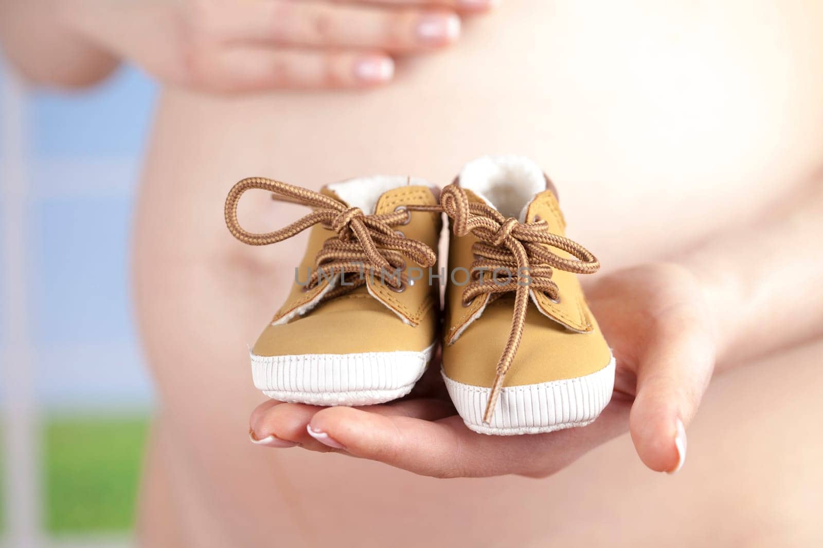 Pregnant woman holding baby shoes in her hands