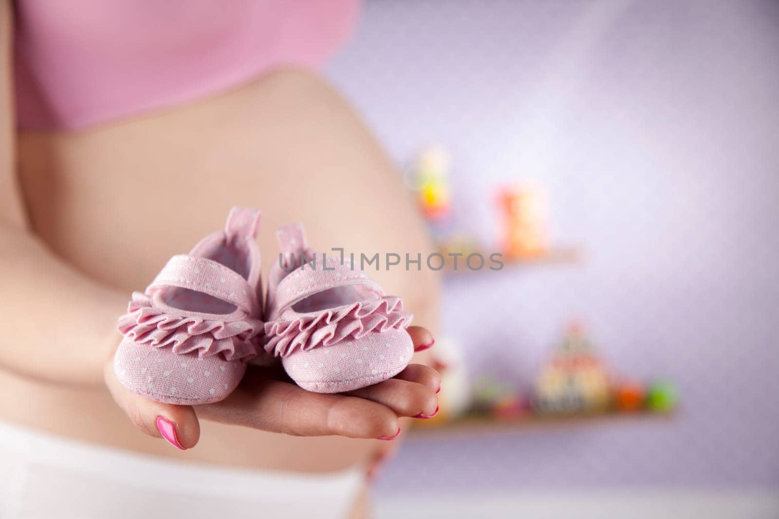 Pregnant woman holding baby shoes in her hands