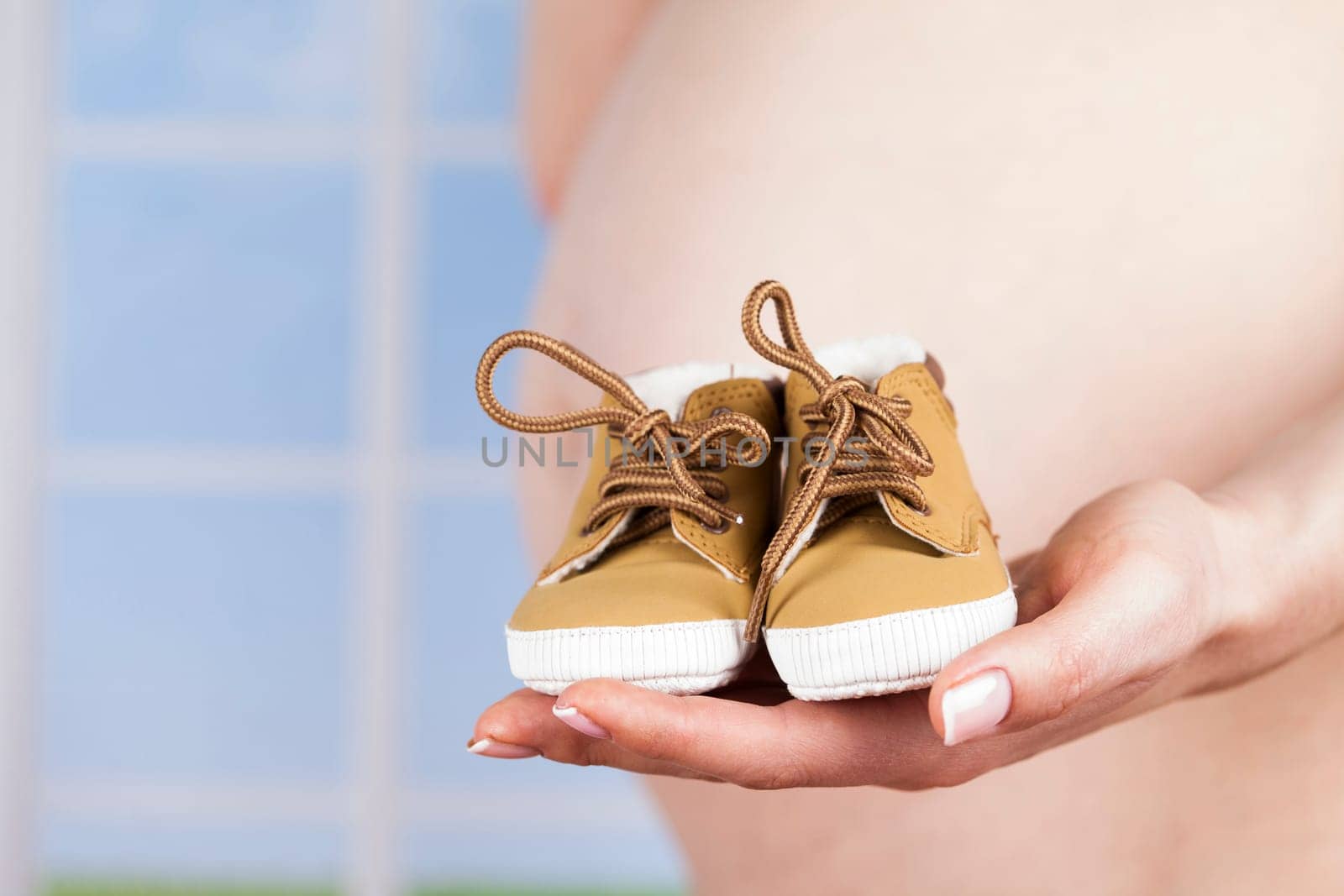 Pregnant woman holding baby shoes in her hands