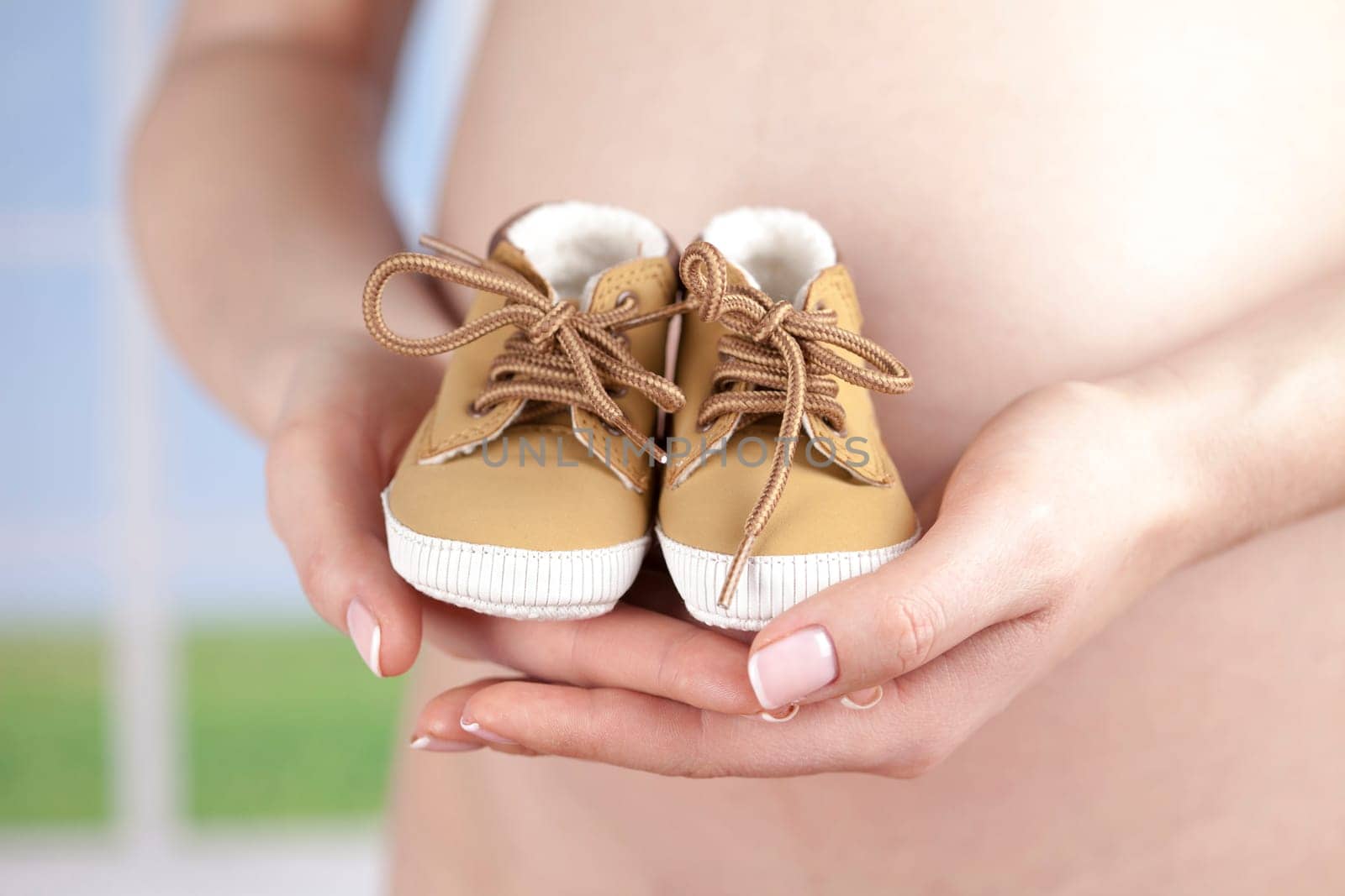 Pregnant woman holding baby shoes in her hands