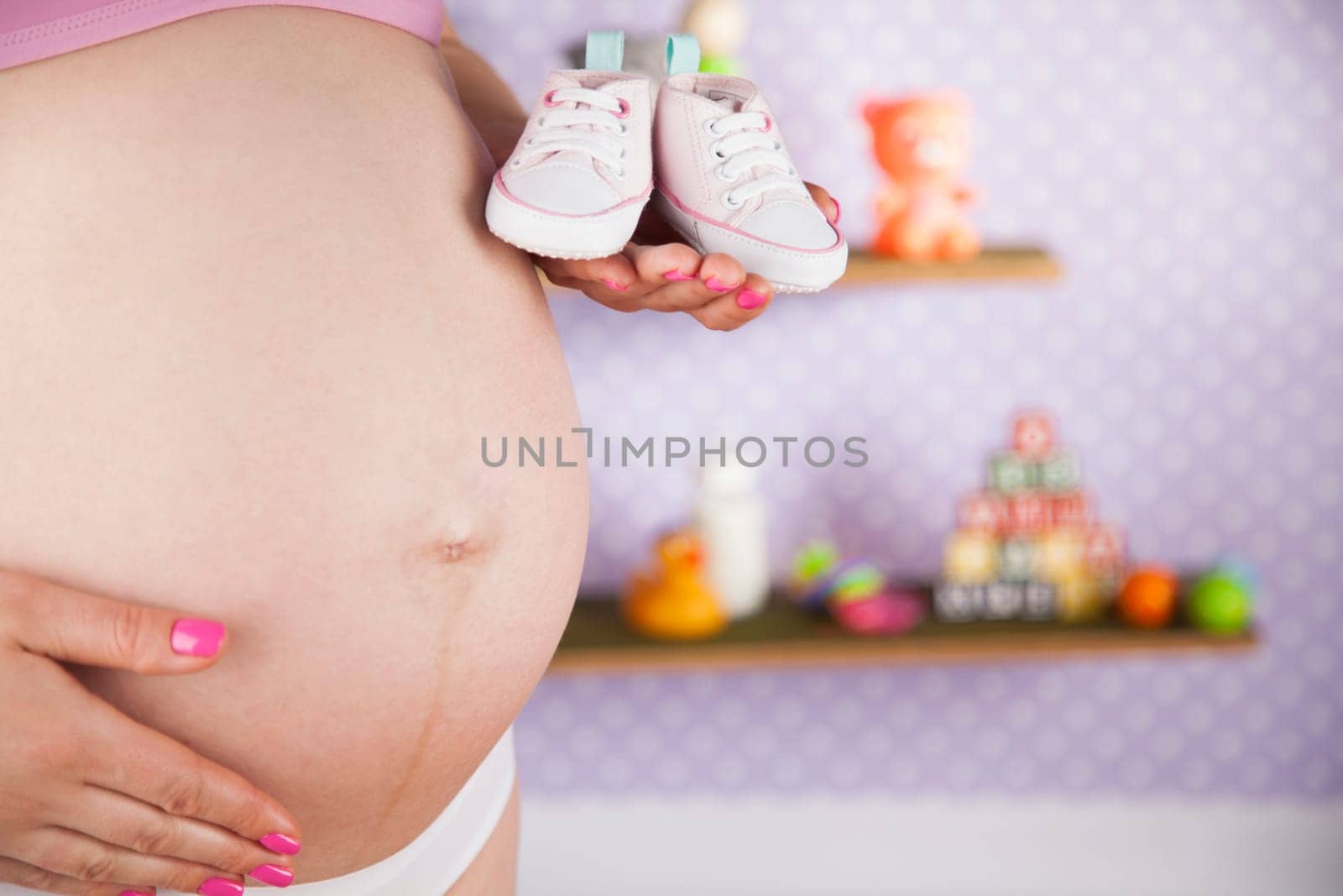 Pregnant woman holding baby shoes in her hands
