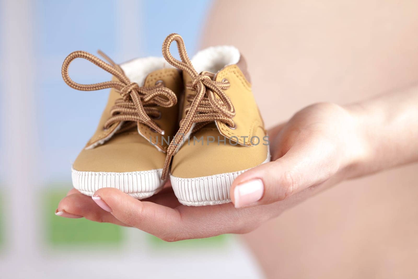Pregnant woman holding baby shoes in her hands