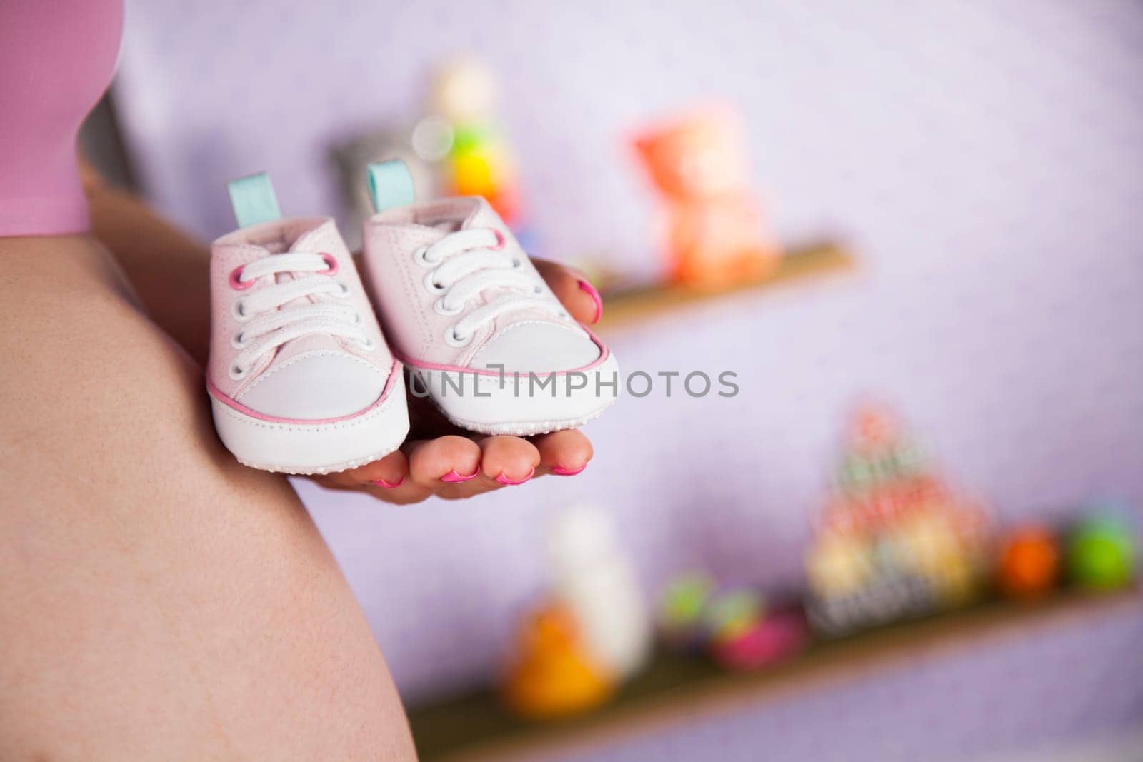 Pregnant woman holding baby shoes in her hands