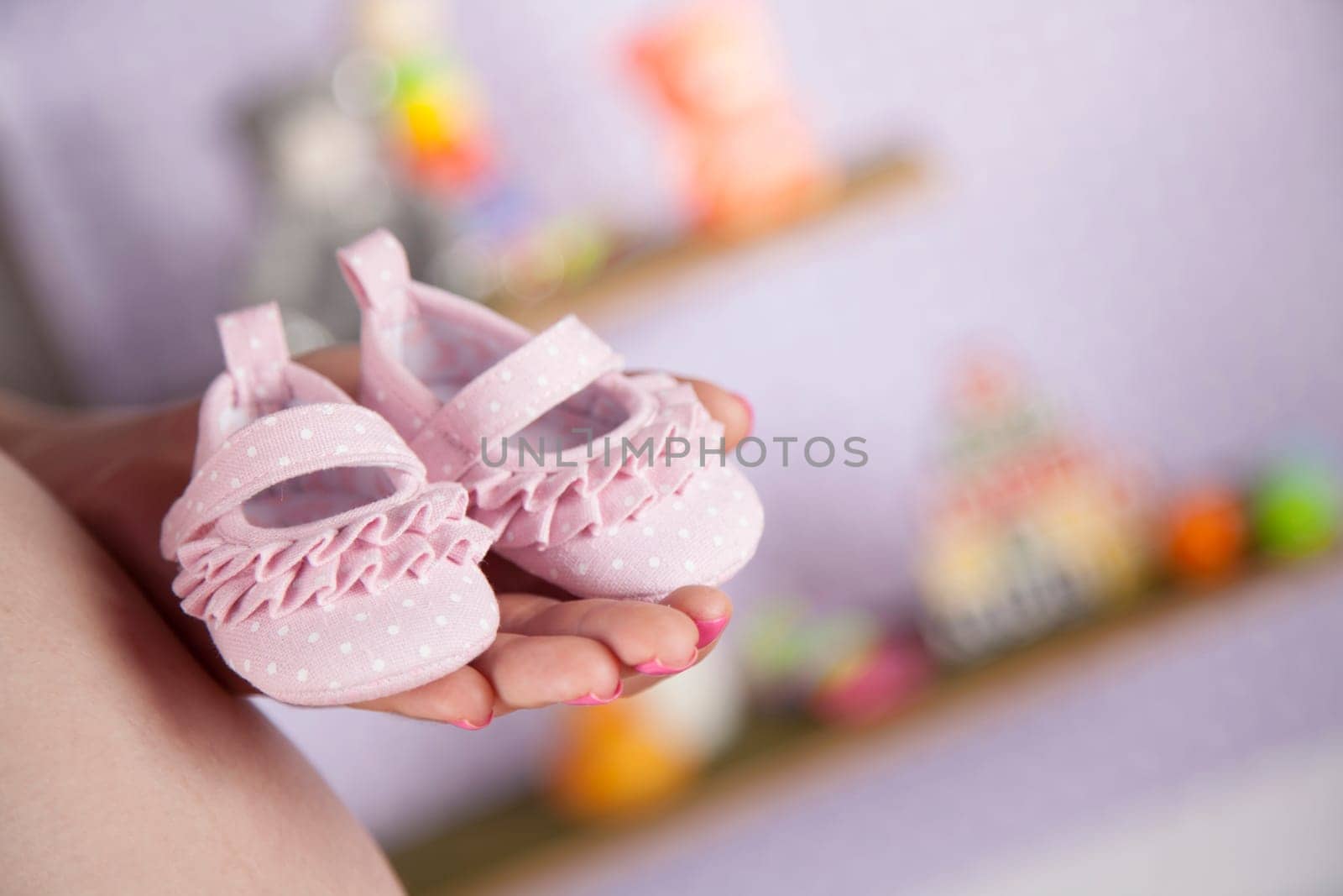 Pregnant woman holding baby shoes in her hands