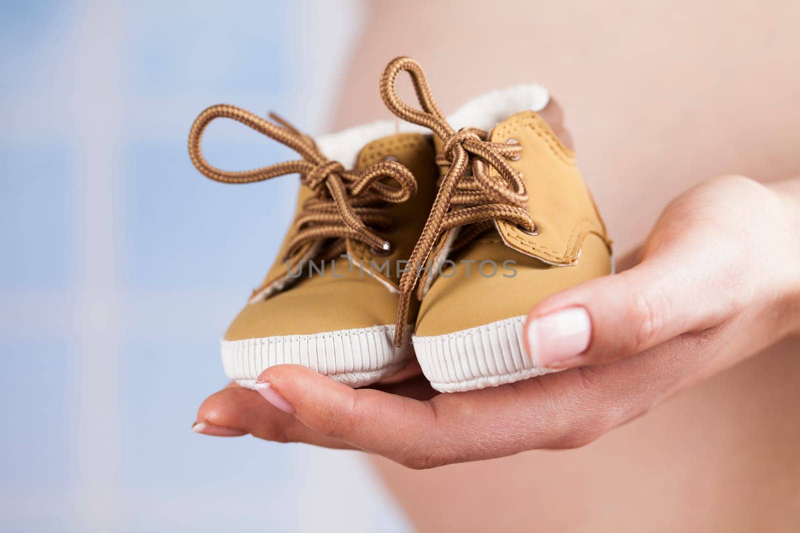 Pregnant woman holding baby shoes in her hands