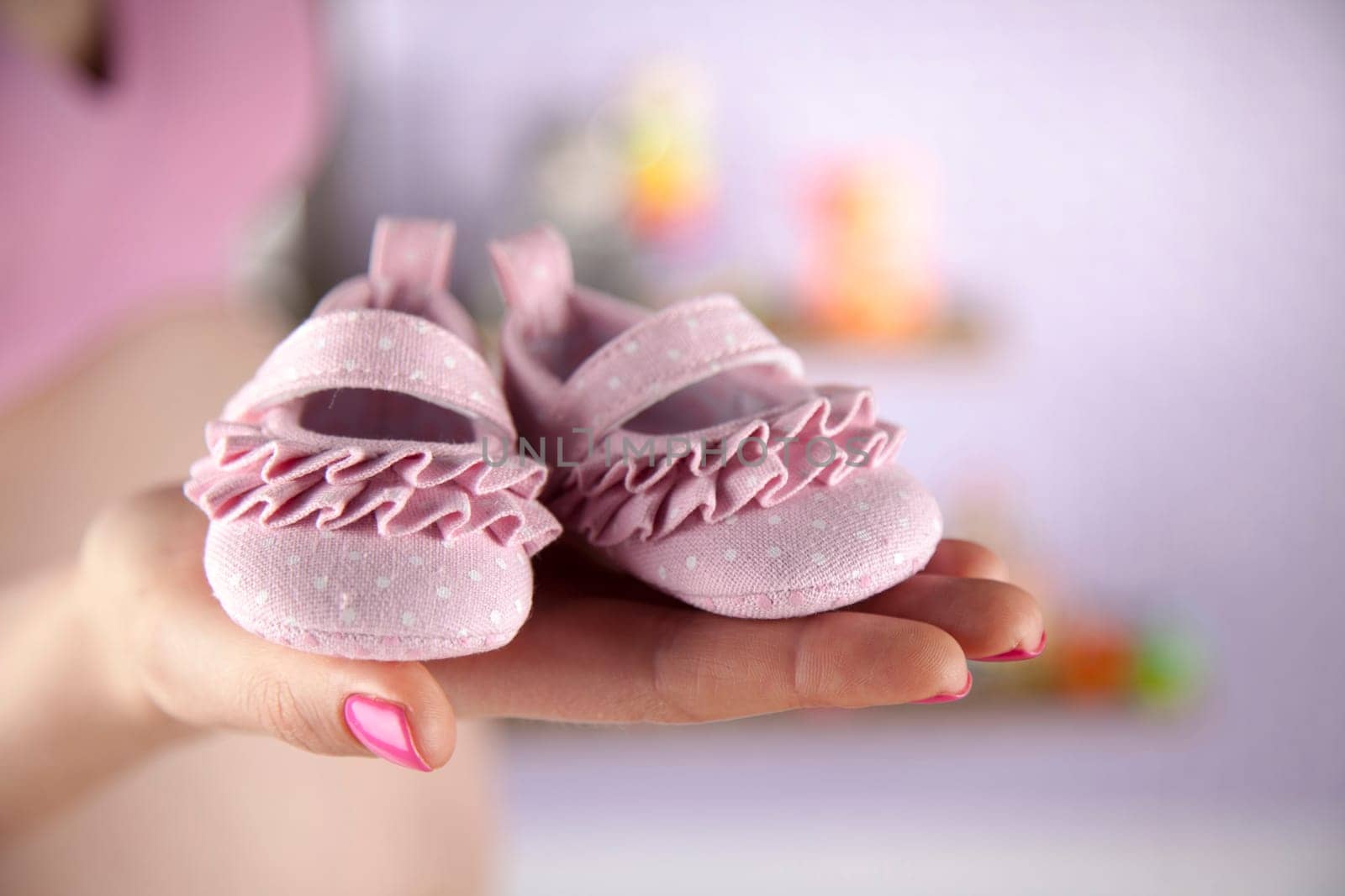 Pregnant woman holding baby shoes in her hands