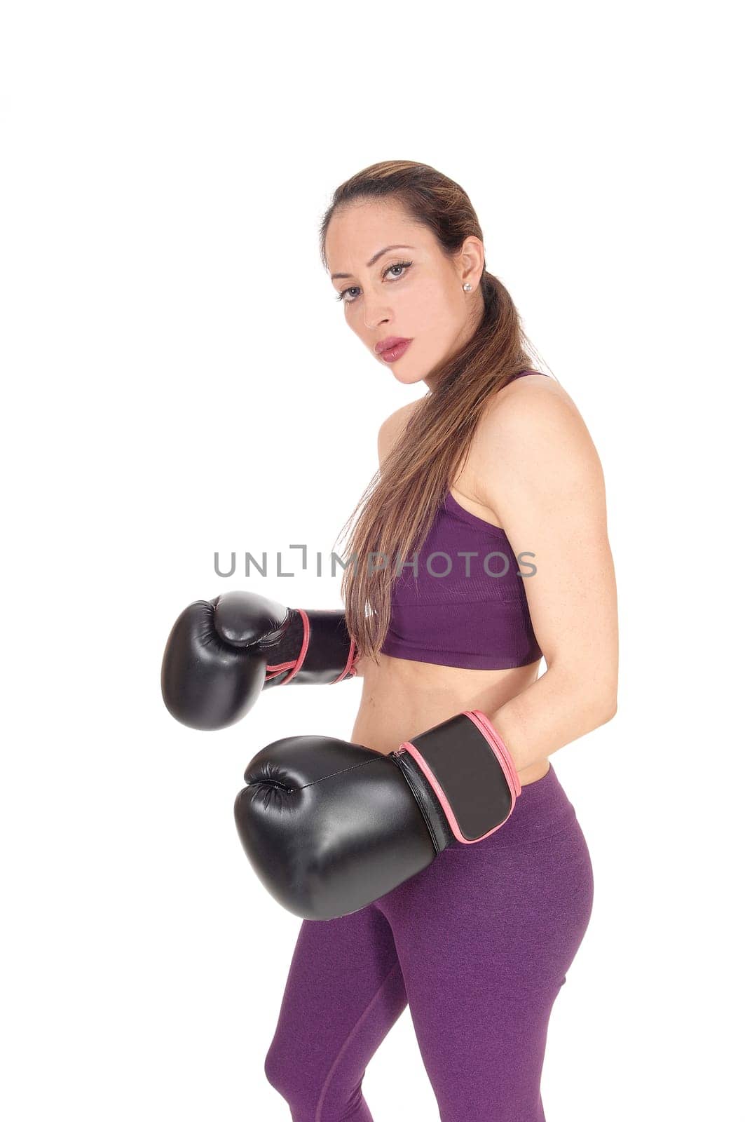 .A beautiful woman serious looking with her arms up in black boxing .cloves ready to give a punch, isolated for white background.