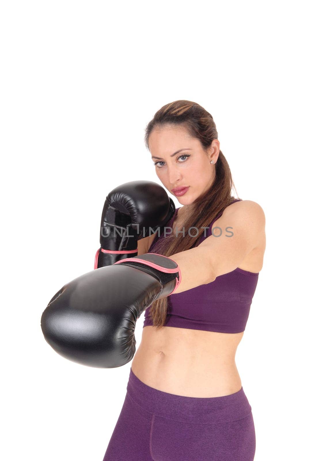 A lovely serious looking woman standing and punching with her black .boxing cloves, isolated for white background.
