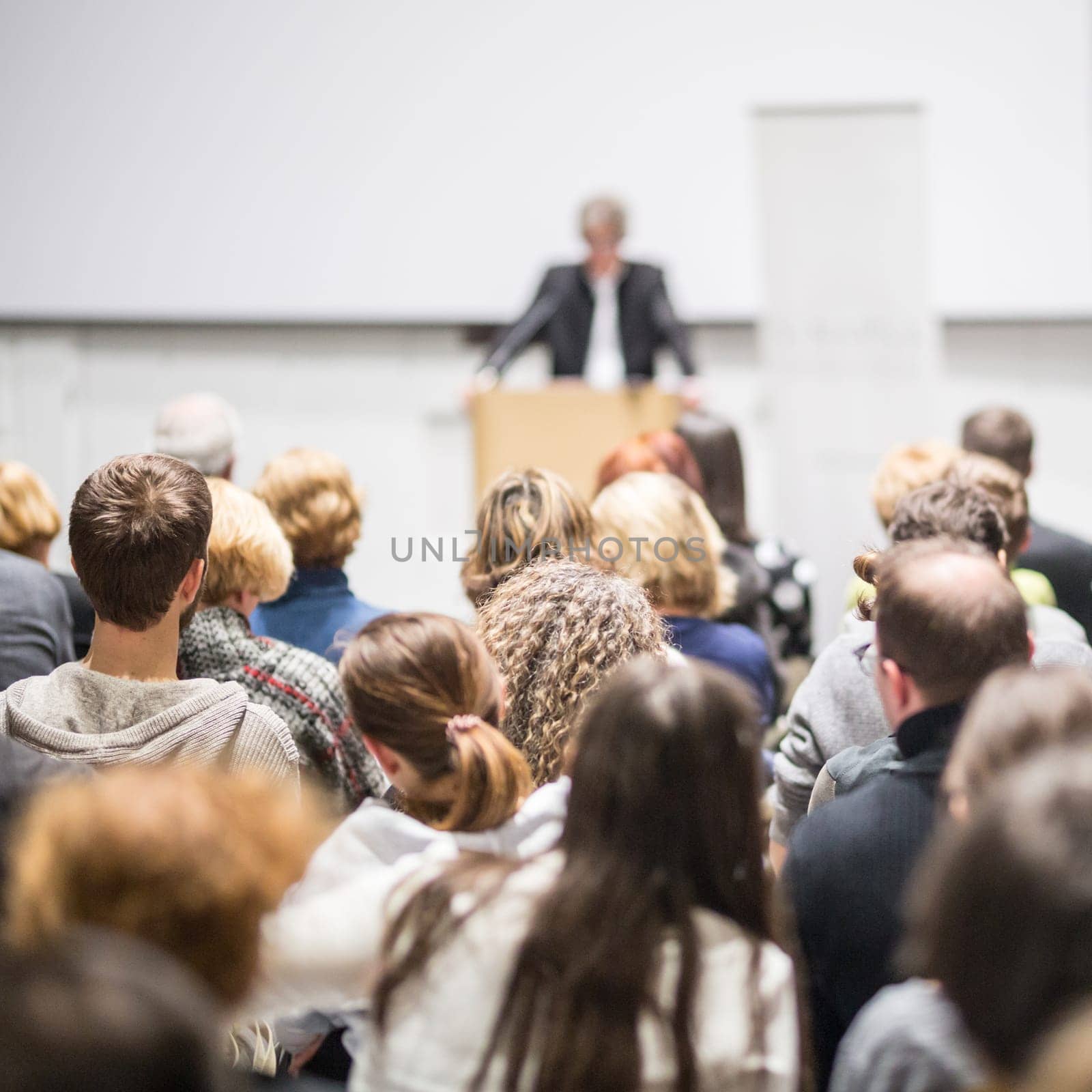 Speaker giving a talk in conference hall at business event. Audience at the conference hall. Business and Entrepreneurship concept. Focus on unrecognizable people in audience.