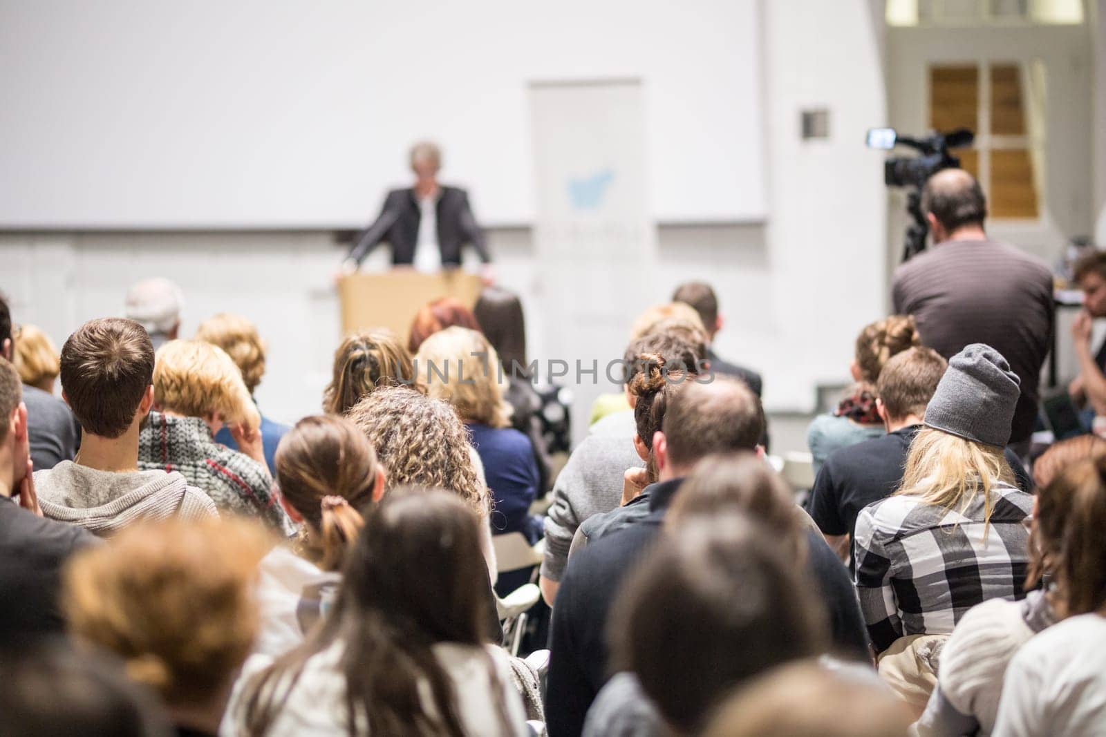 Speaker giving a talk in conference hall at business event. Audience at the conference hall. Business and Entrepreneurship concept. Focus on unrecognizable people in audience.