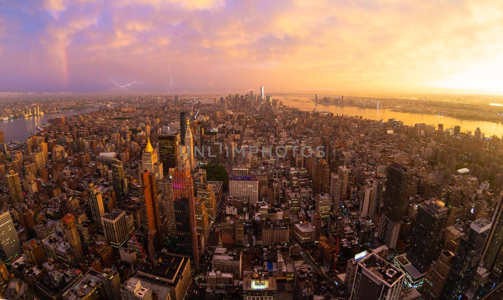 New York City skyline with Manhattan skyscrapers at dramatic vibrant after the storm sunset, USA. Rainbow and lightnings can be seen in background over Brooklyn bridge.