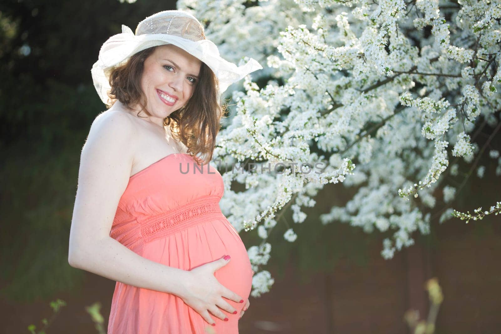 Young beautiful pregnant woman, blooming garden