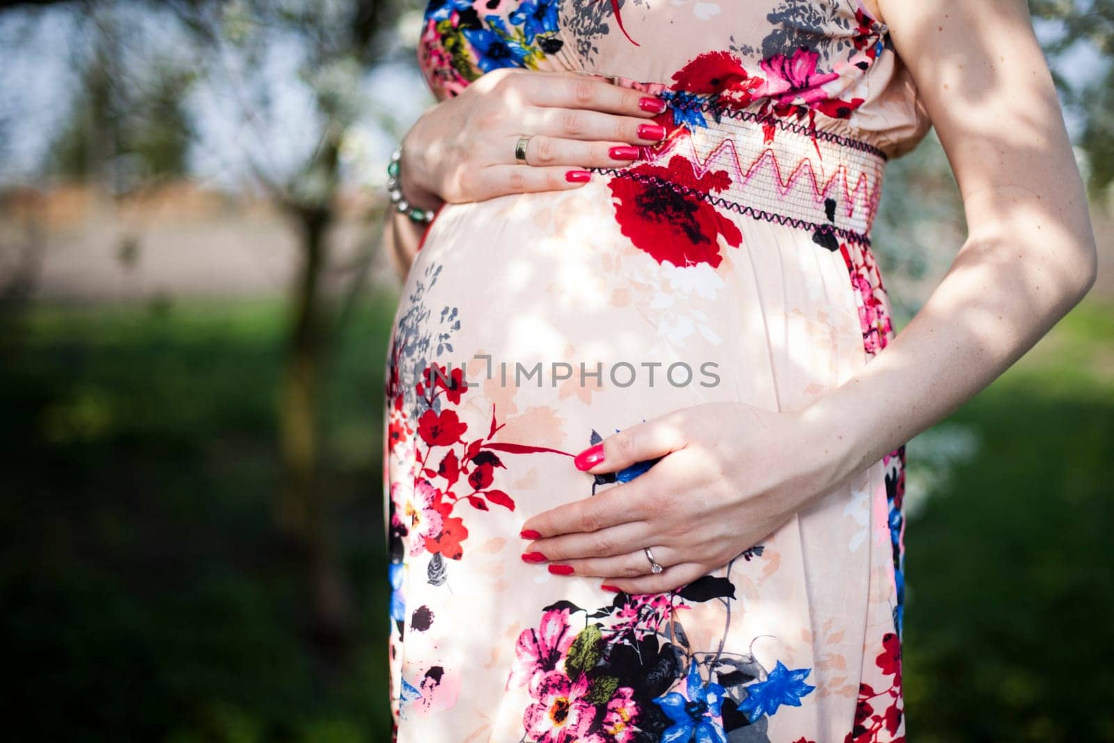 Young beautiful pregnant woman, blooming garden