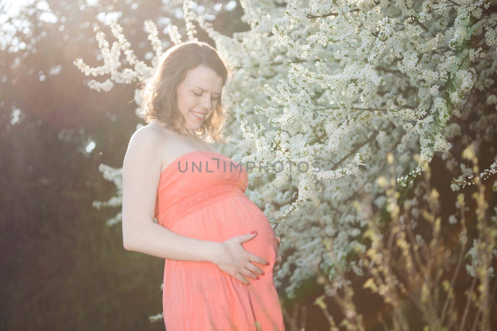 Young beautiful pregnant woman, blooming garden
