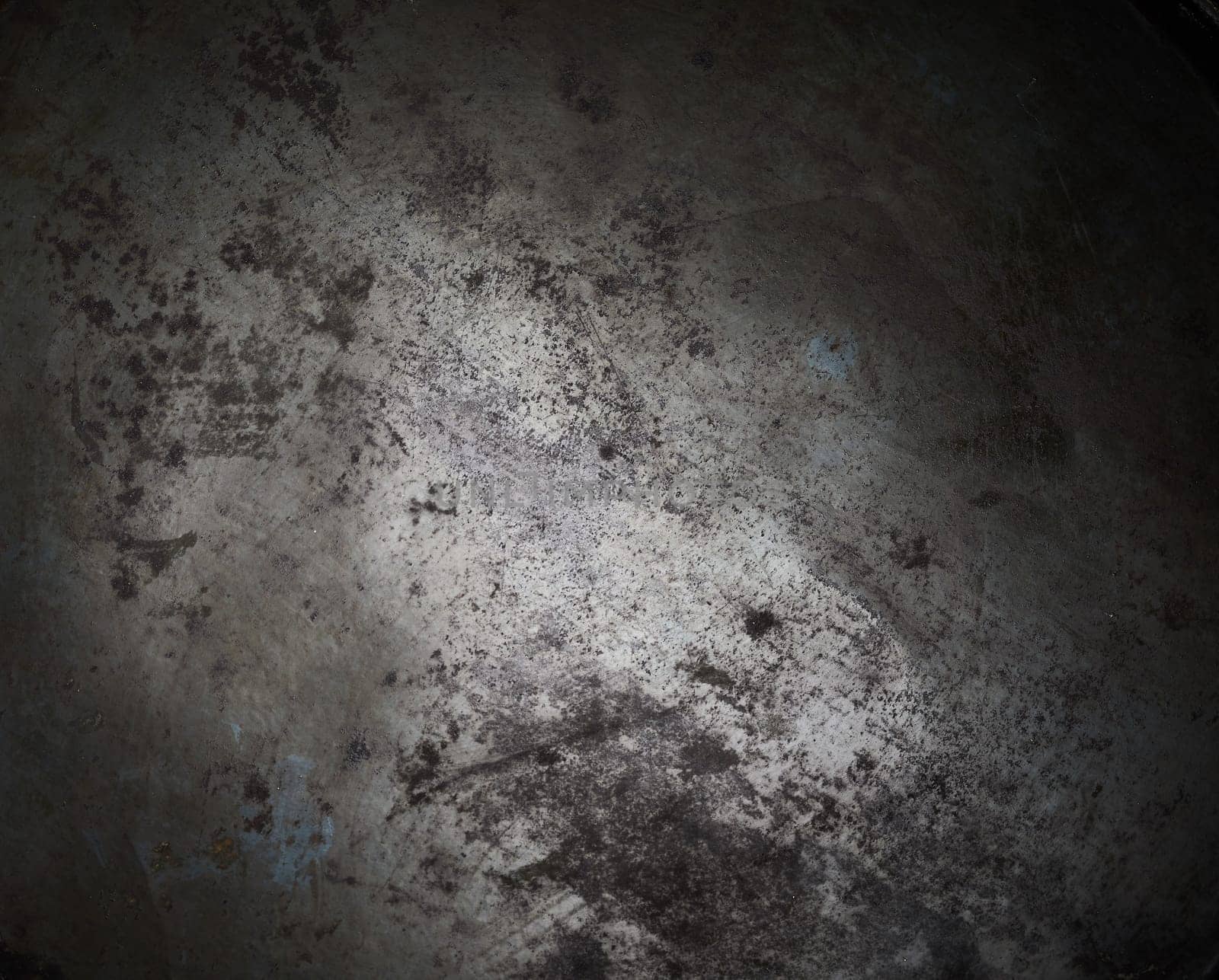 Background texture of blackened burnt metal on a vintage or rustic kitchen utensil with vignette and central highlight for copy space