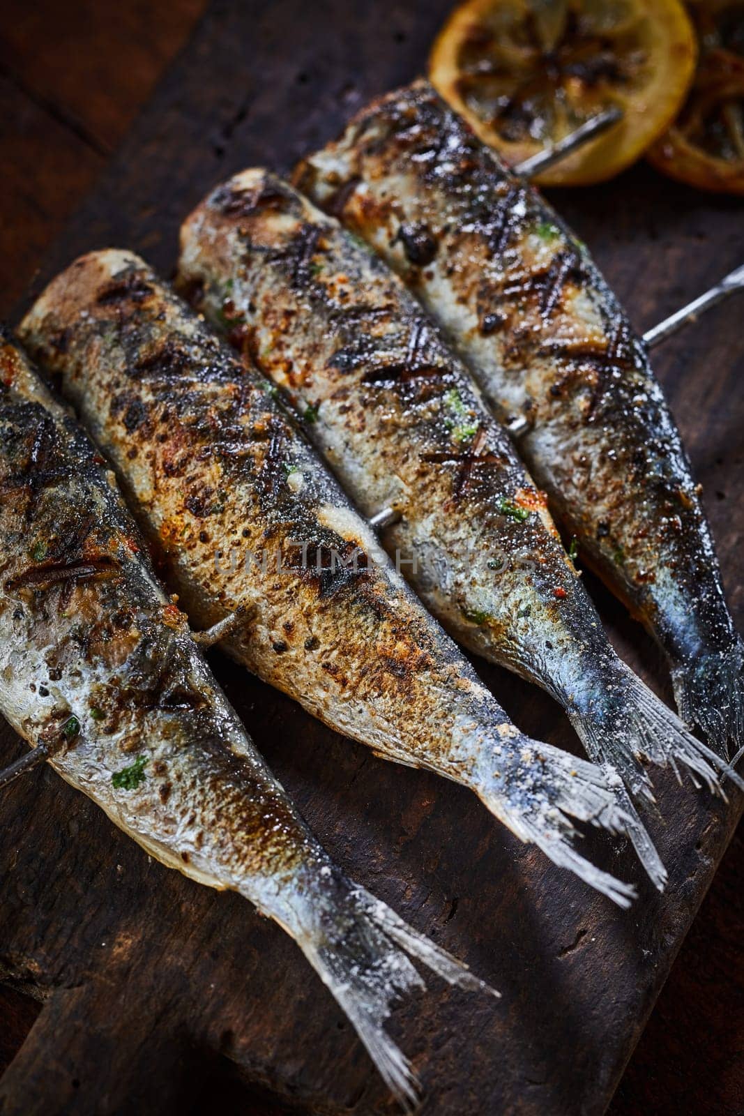 Grilled fish on metal skewers in close-up viewed from above