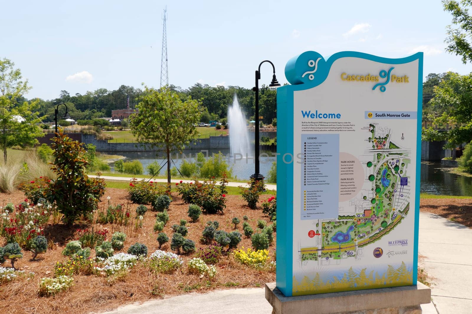 Tallahassee, FL, USA - May 13, 2018: Cascades Park entrance sign and landscape.View of Cascades Park beautiful landscape with lake fountain. Sunny day at Cascades Park in Tallahassee with sign and map