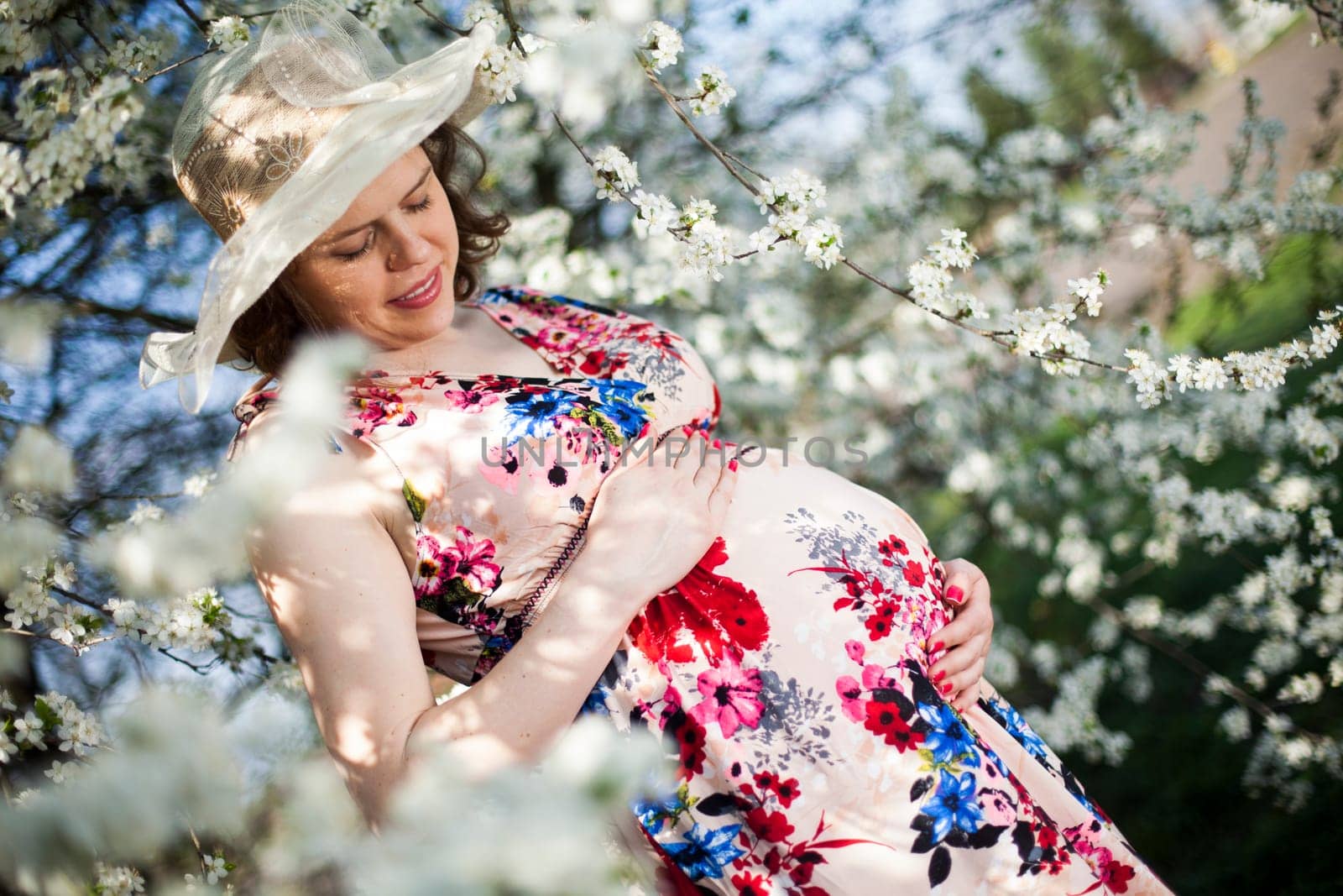 Young beautiful pregnant woman, blooming garden
