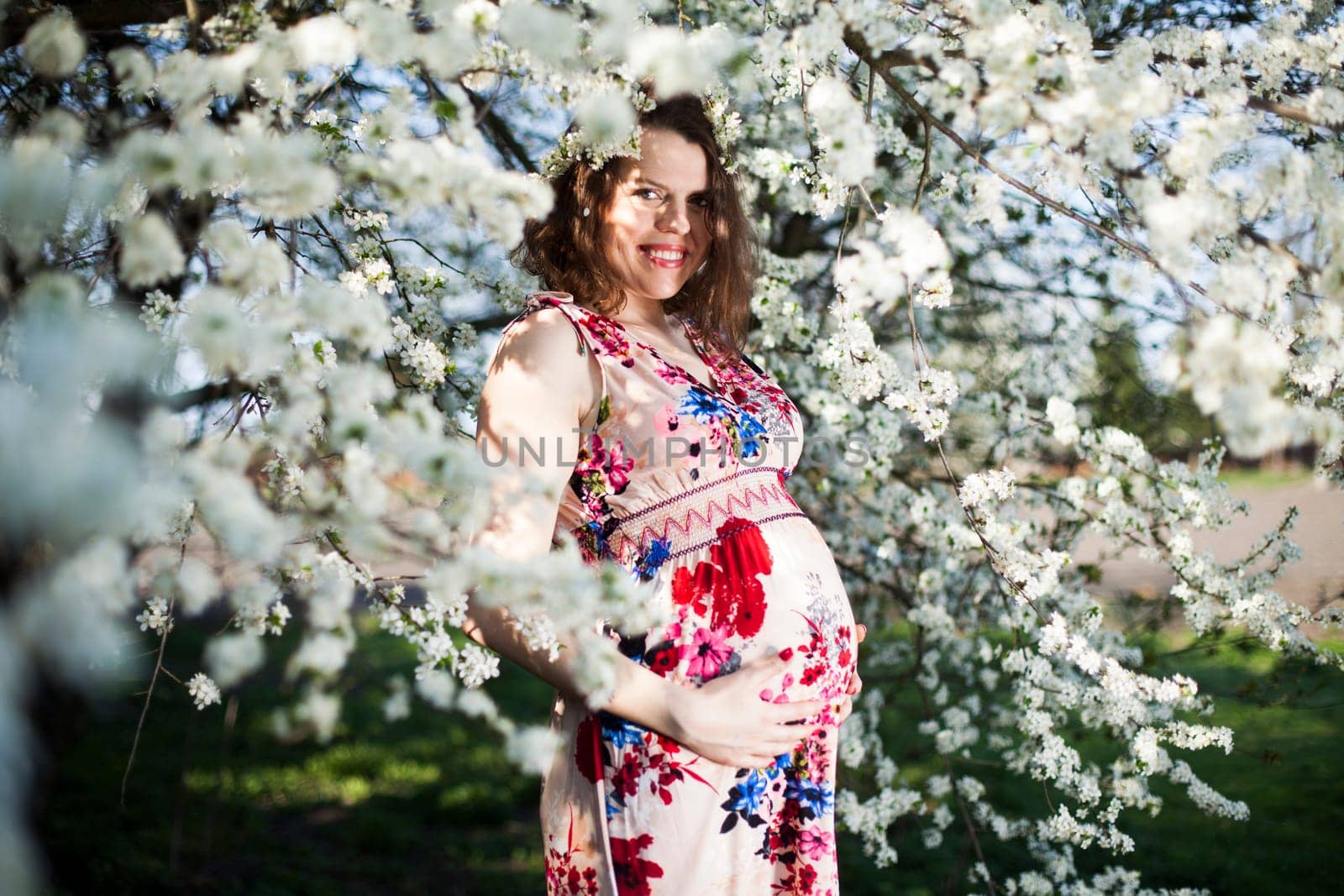Young beautiful pregnant woman, blooming garden