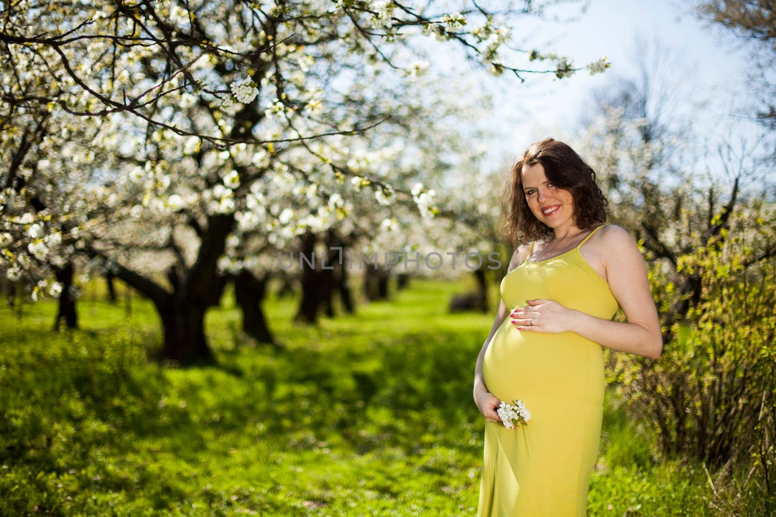 Beautiful pregnant woman relaxing outside in the Orchard