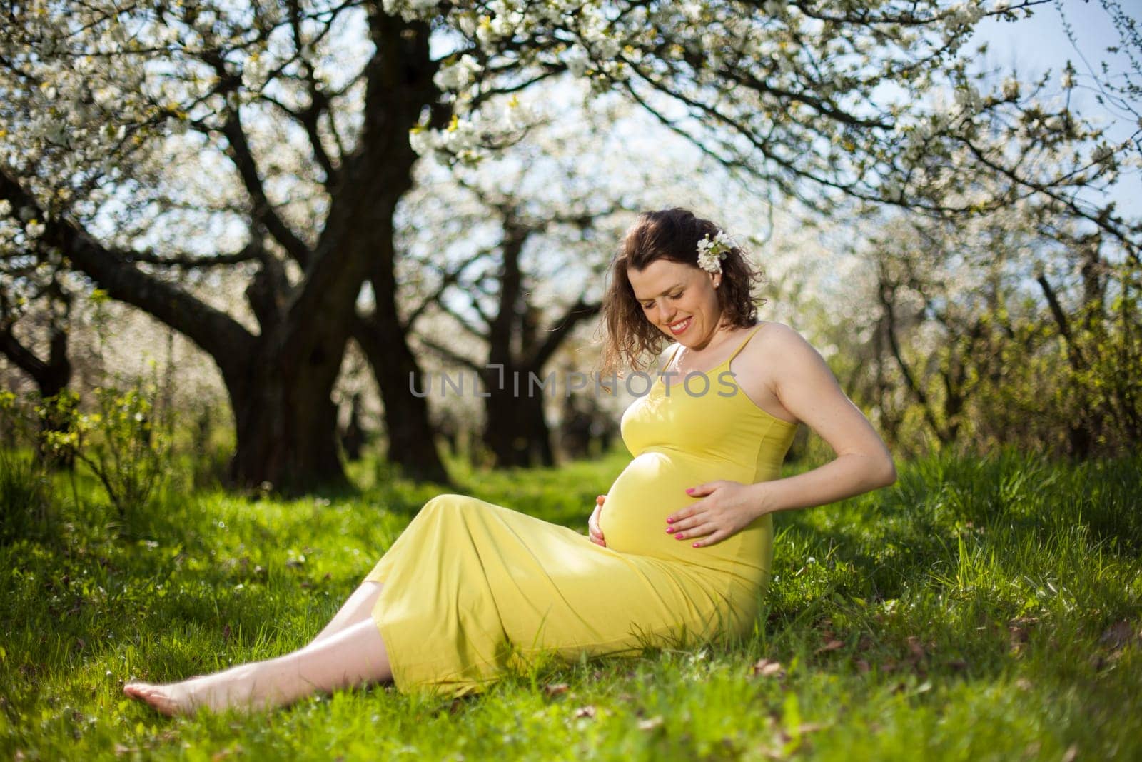 Beautiful pregnant woman relaxing outside in the Orchard