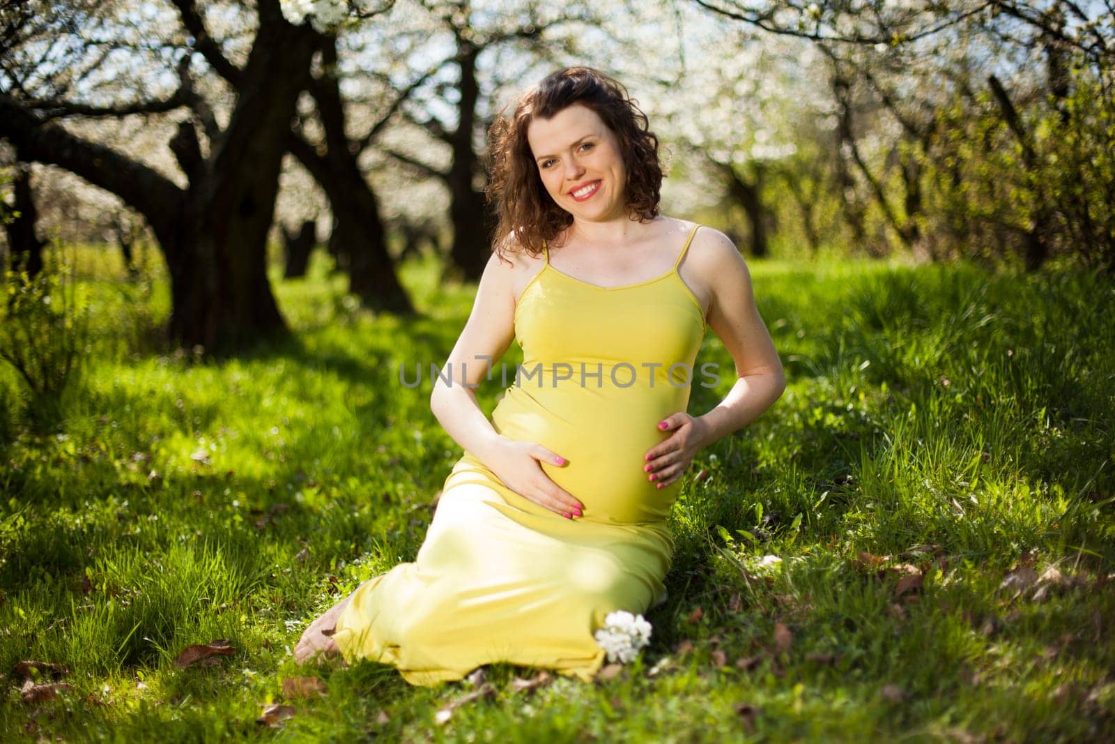 Beautiful pregnant woman relaxing outside in the Orchard