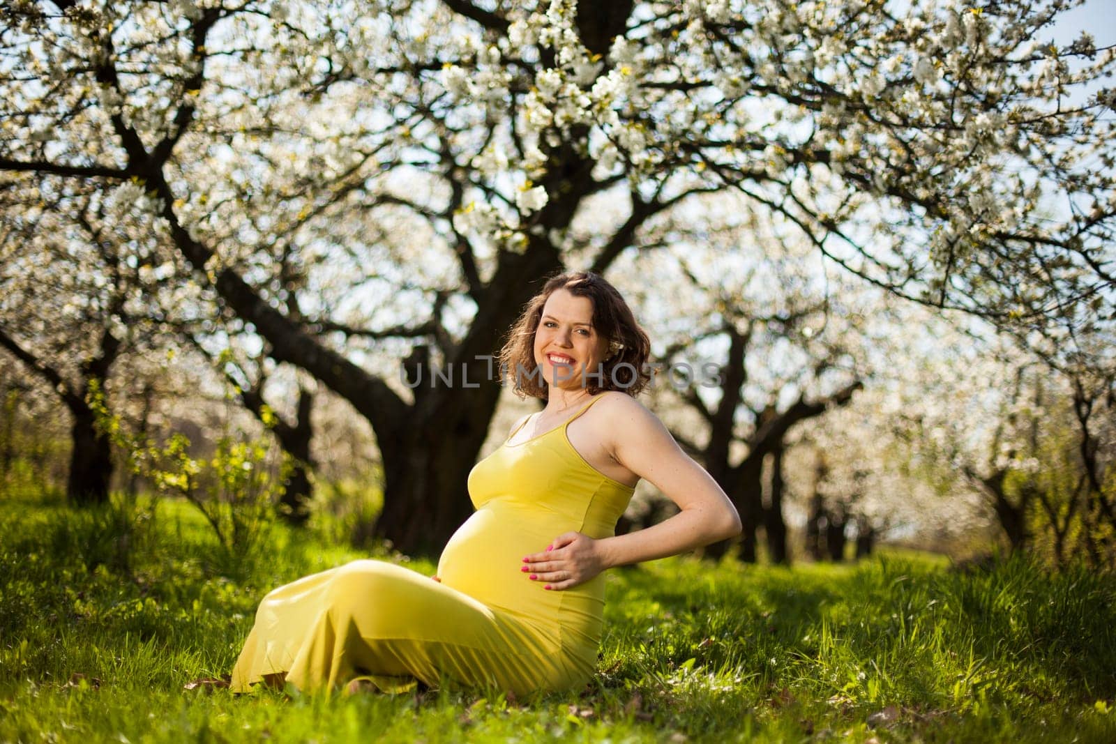 Beautiful pregnant woman relaxing outside in the Orchard