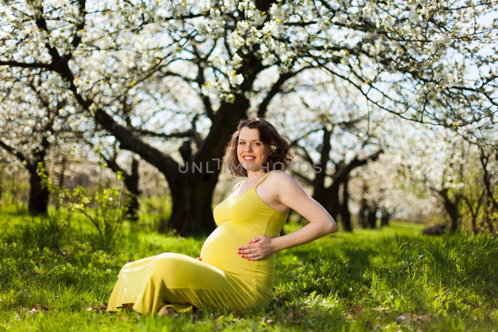 Beautiful pregnant woman relaxing outside in the Orchard