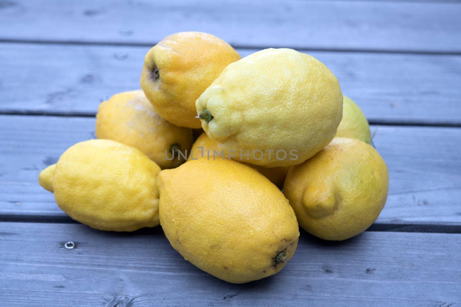 pile of yellow lemons on wooden ground