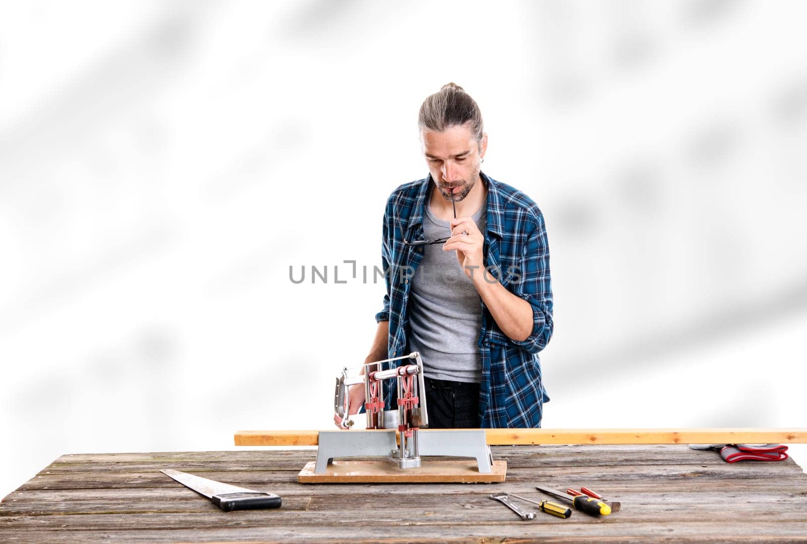 worker in blue plaid  shirt sawing wood