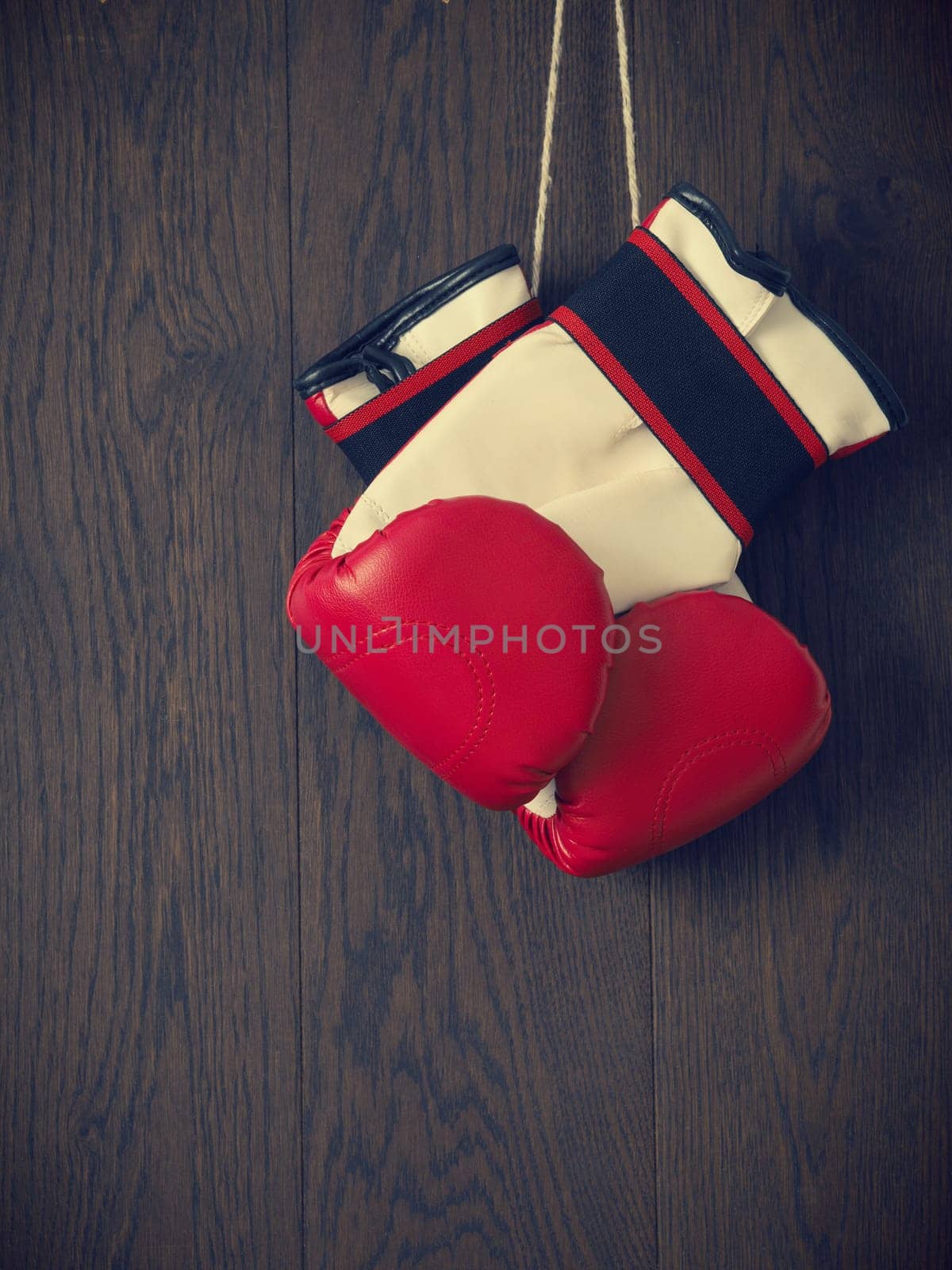 Red boxing gloves on a rustic wooden wall, sports or assertiveness concept