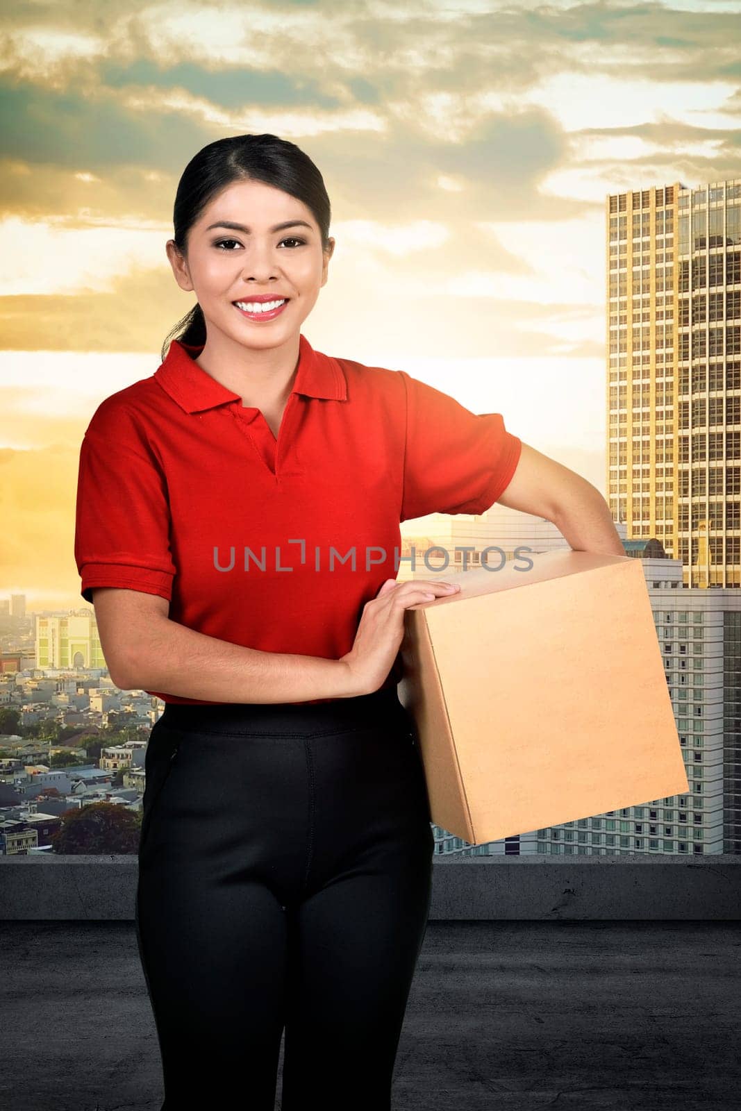 Smiling asian delivery woman carrying the parcel on the city