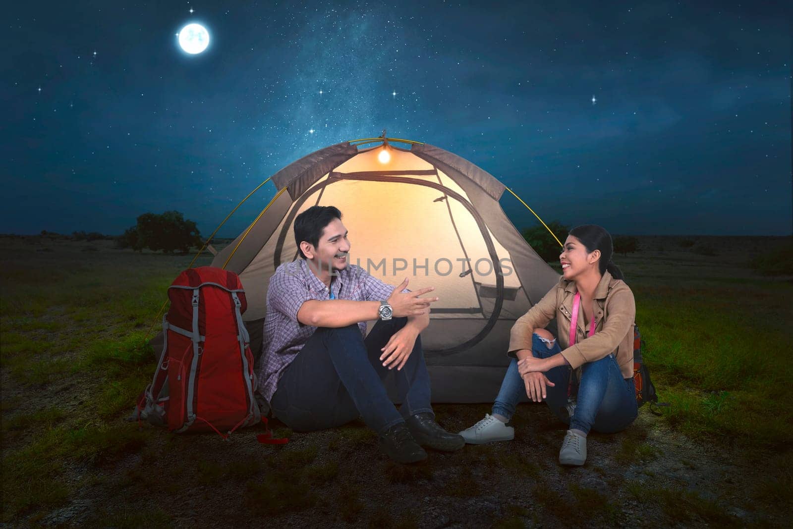 Attractive asian couple relaxing in front of the tent at night