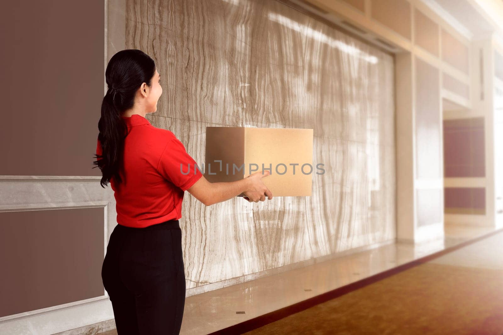 Attractive asian female courier with the box on the modern building