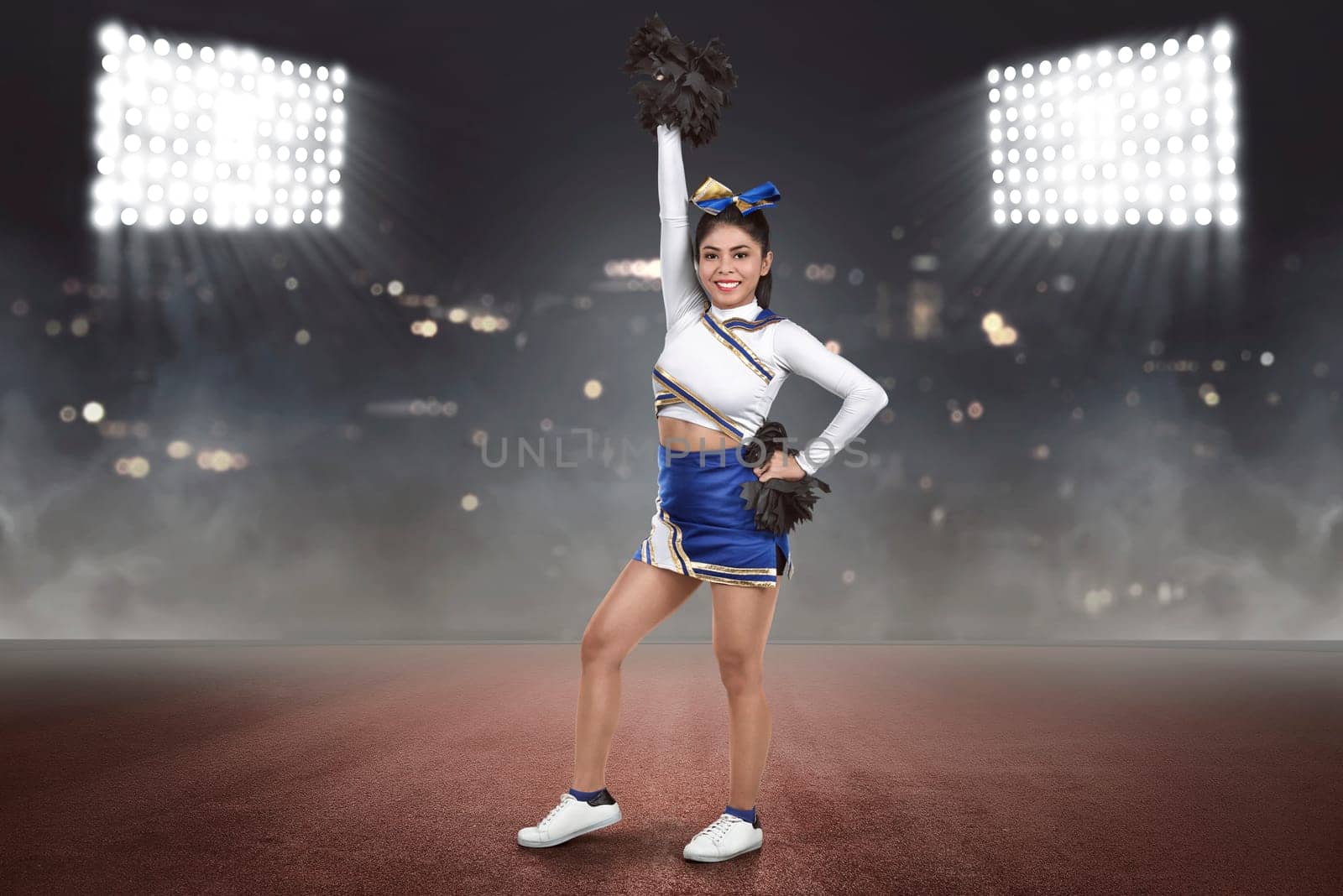 Young asian cheerleader action with pom-poms on the stadium