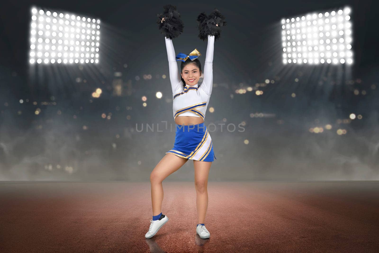 Pretty asian cheerleader with hands holding pom-poms in the air on the stadium