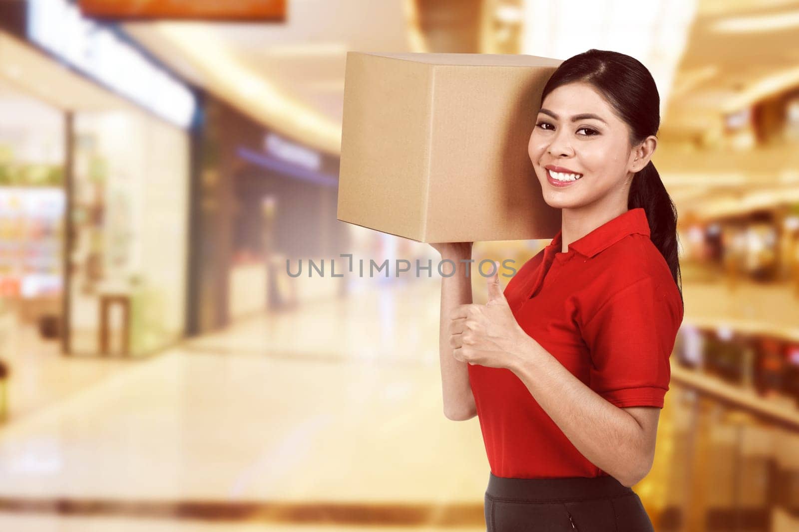 Beautiful asian female delivery holding the package with blurred background