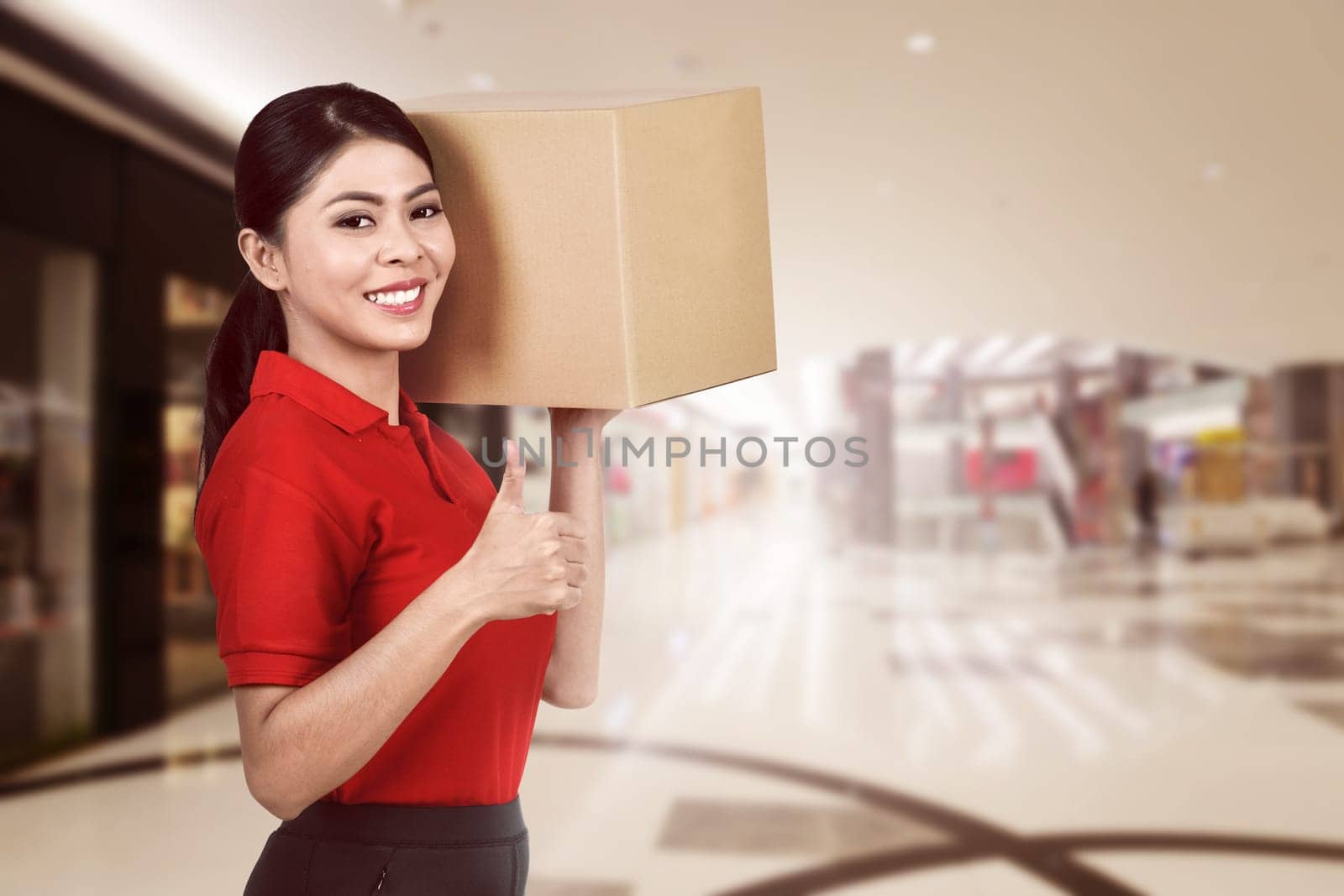 Smiling asian courier woman carrying the parcel to deliver
