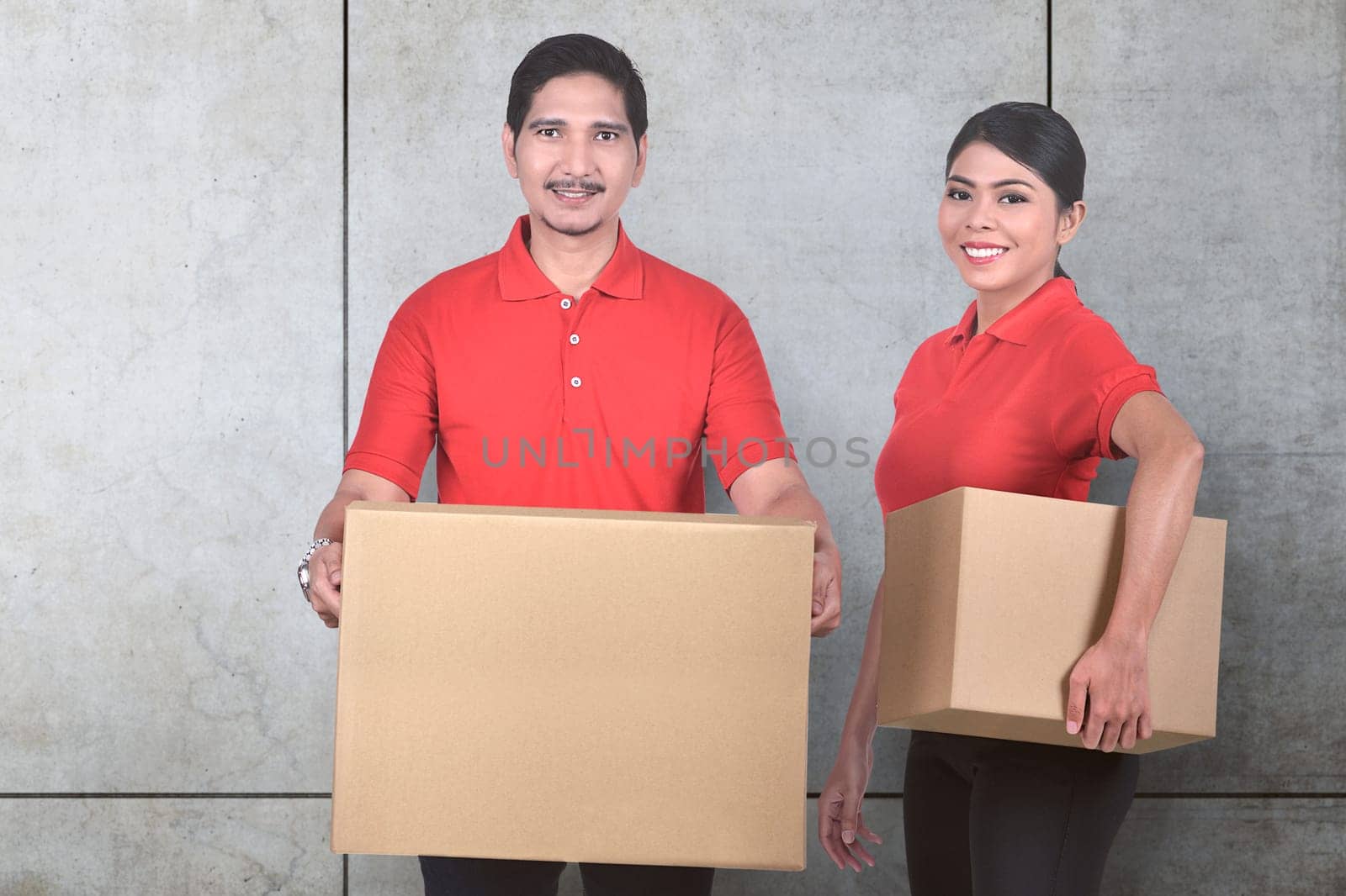 Young asian delivery service team with the parcel standing over wall background
