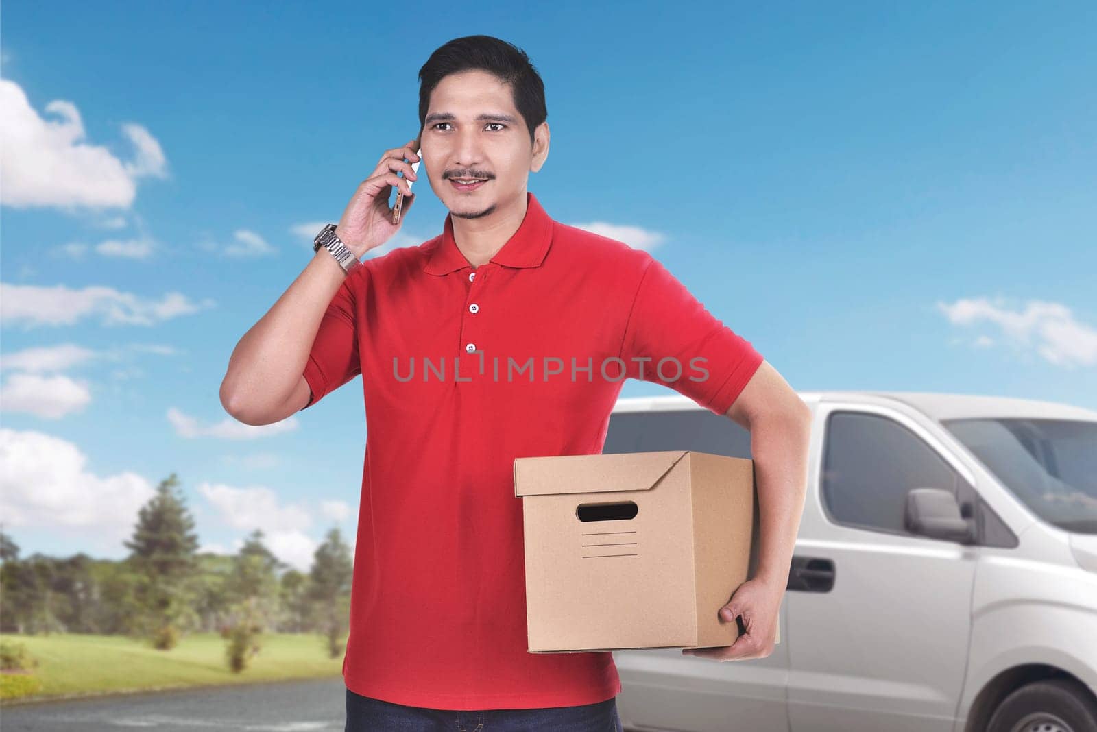 Handsome asian male courier with phone bring the parcel with van on the background