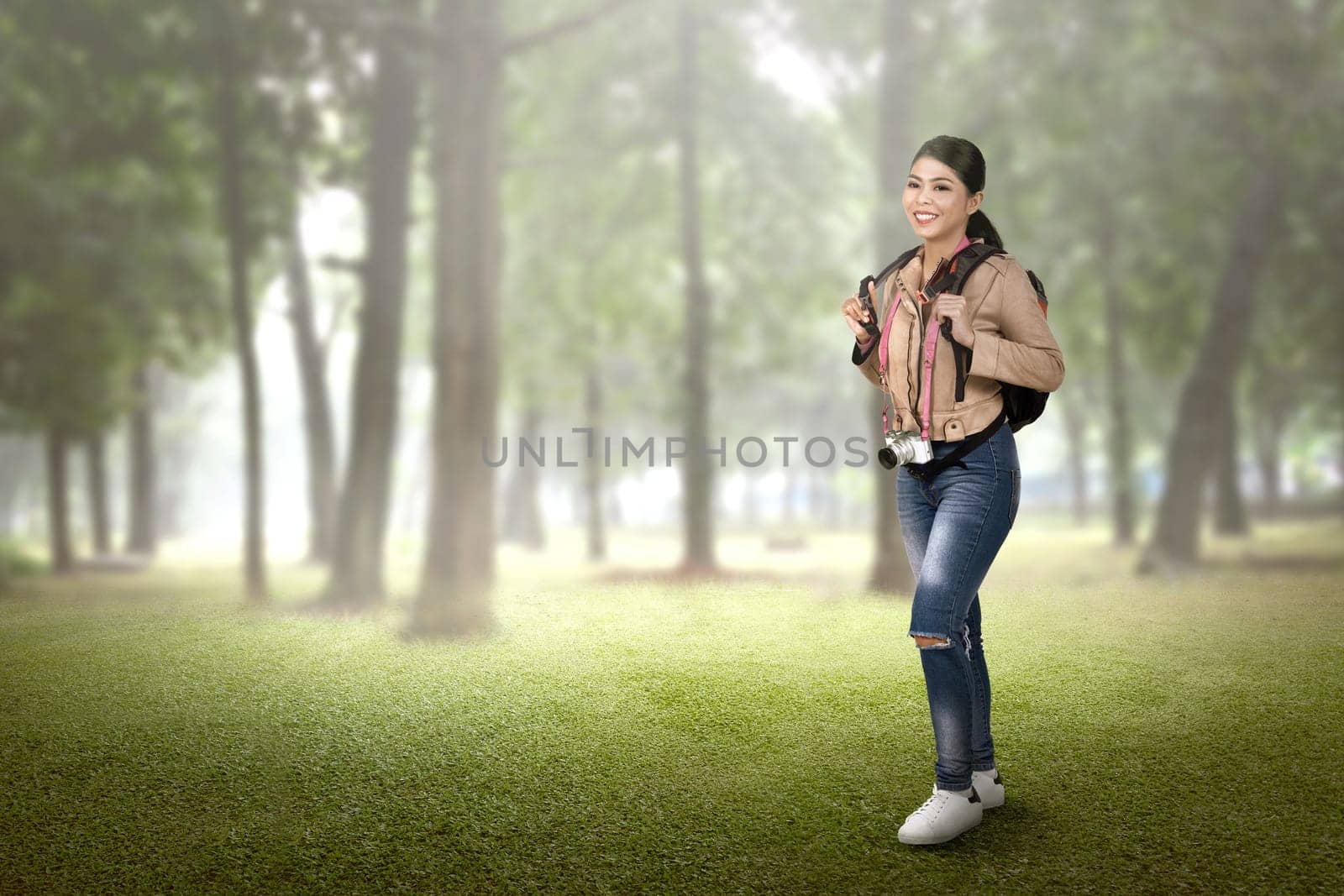 Pretty asian tourist woman with backpack and camera walking on the forest