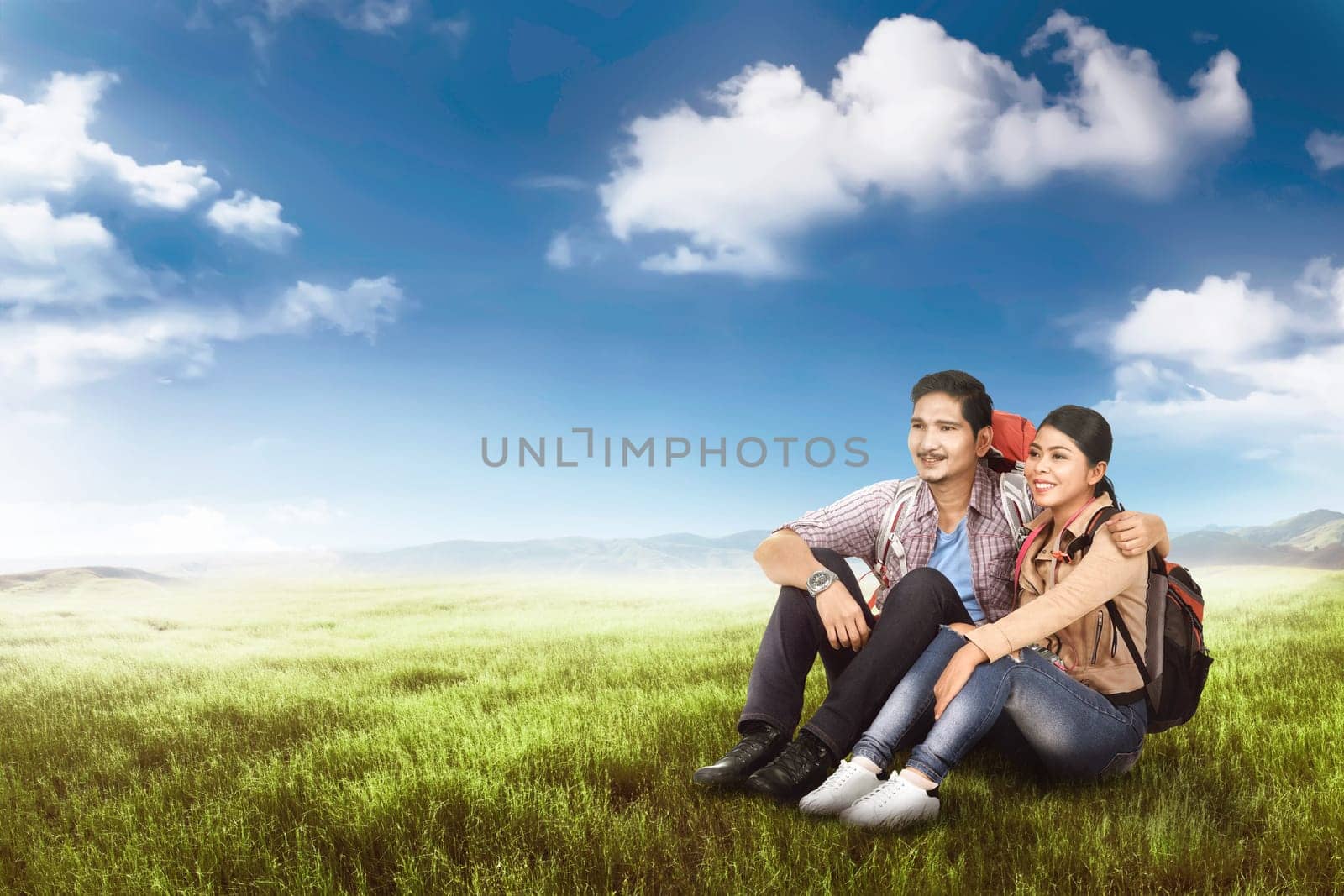 Romantic asian backpacker couple sitting and enjoying the view at meadow