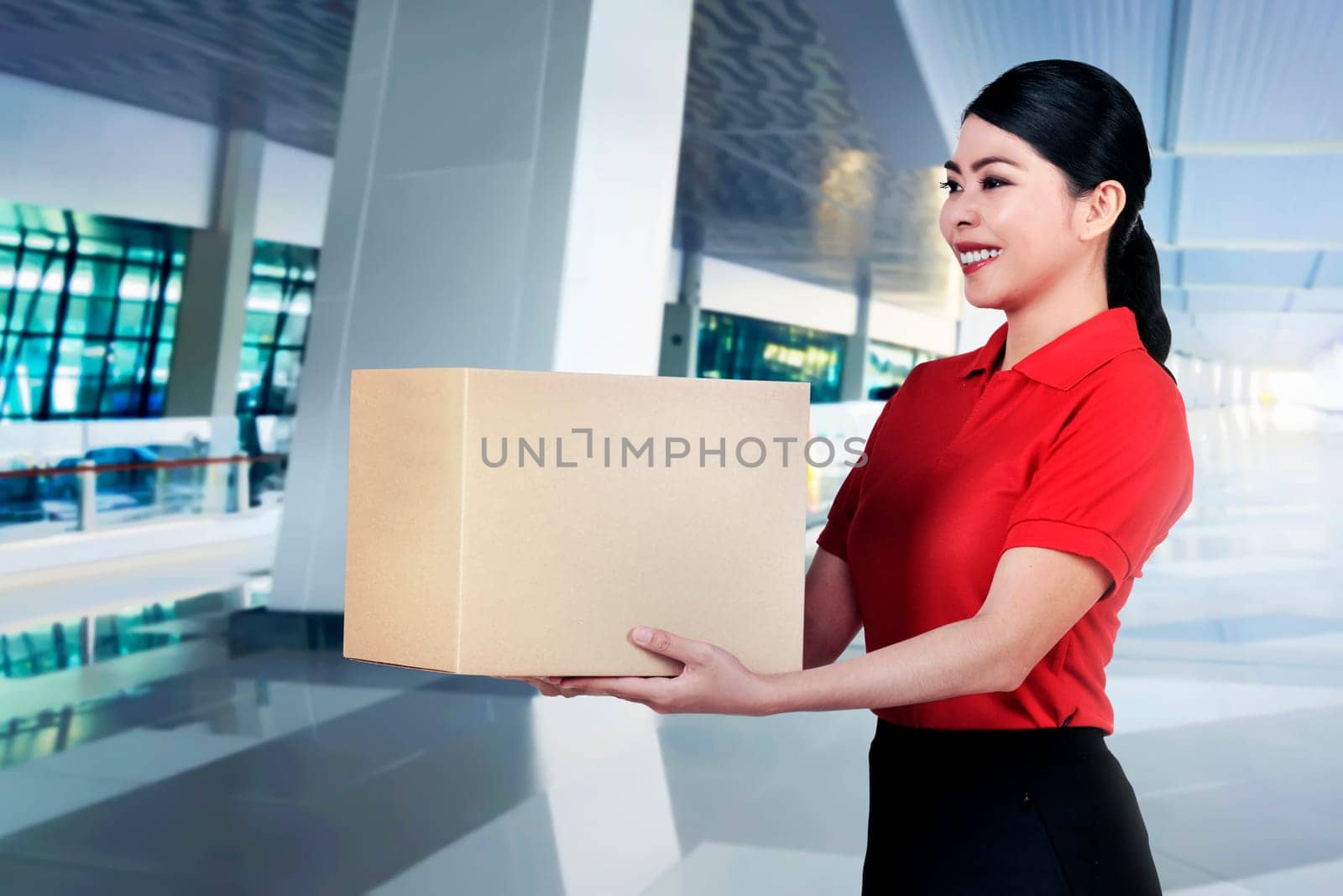 Beautiful asian courier woman bring the parcel on the office building