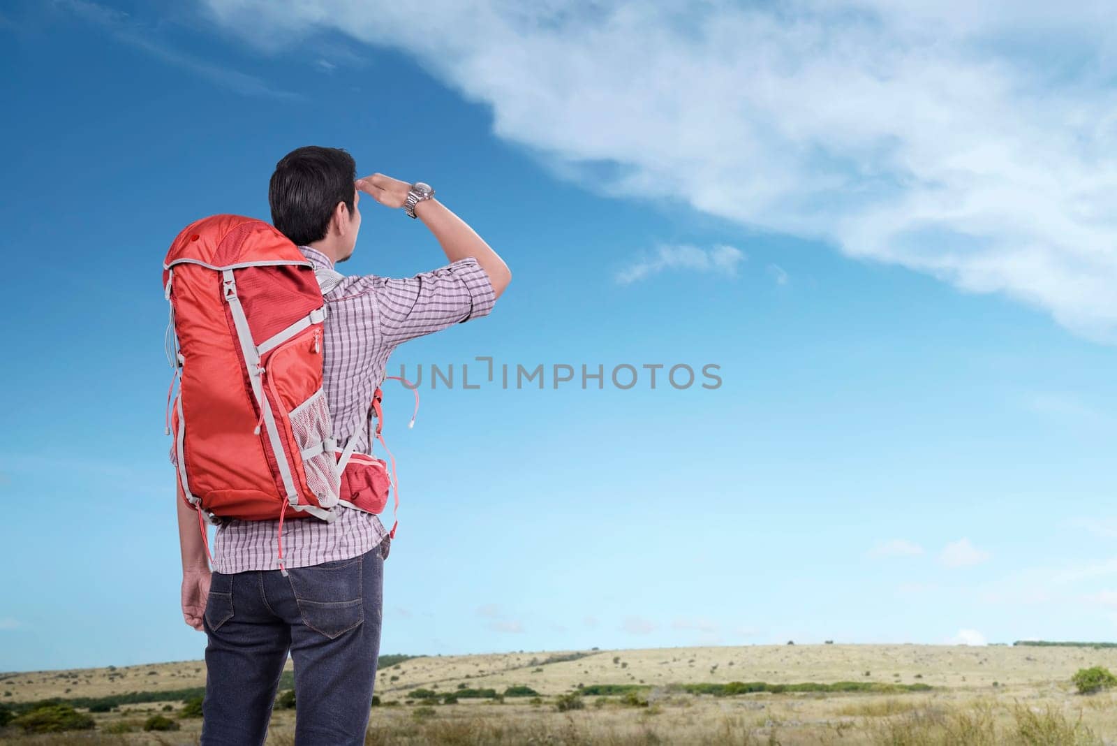 Young asian tourist man with backpack looking at blue sky at sunny day